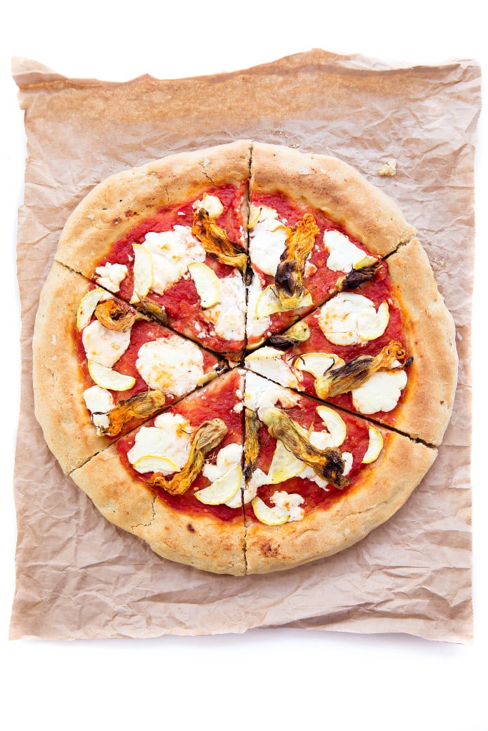 A perfect summer pizza made with crushed tomatoes, mozzarella, and squash blossoms!