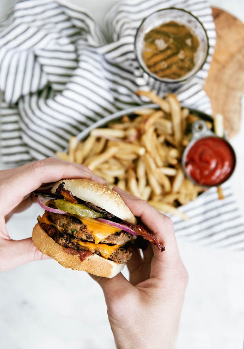 holding a Bourbon Bacon BBQ Burger