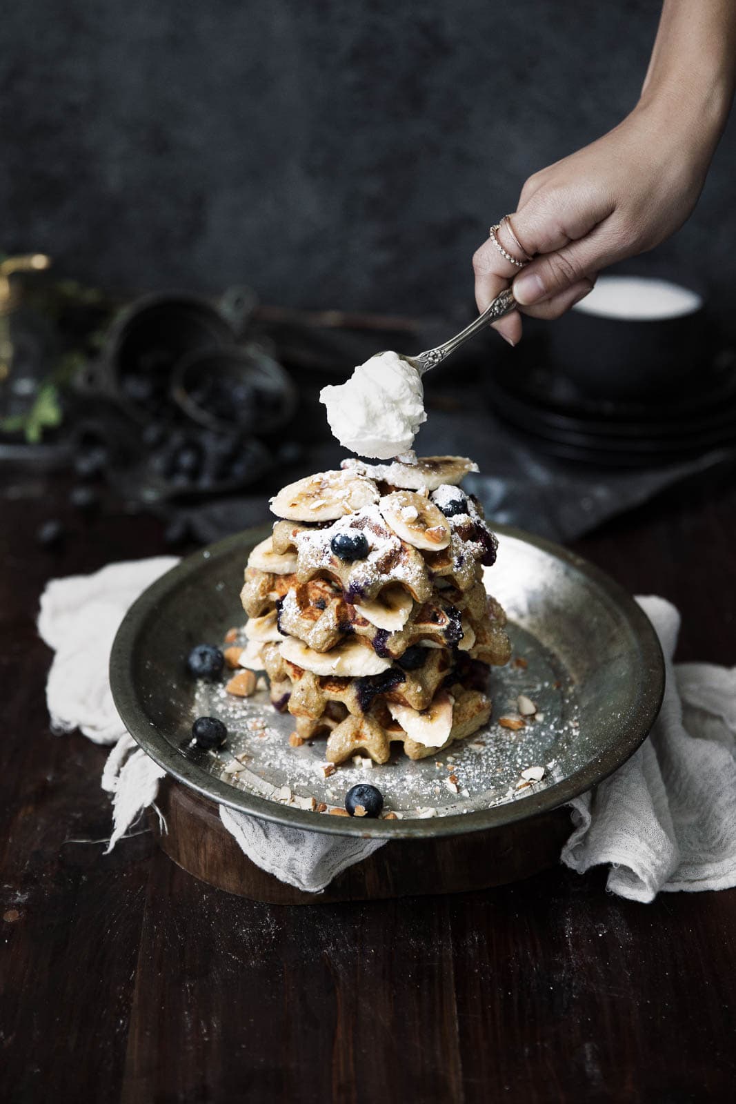 dolloping whipped cream onto gluten free waffles