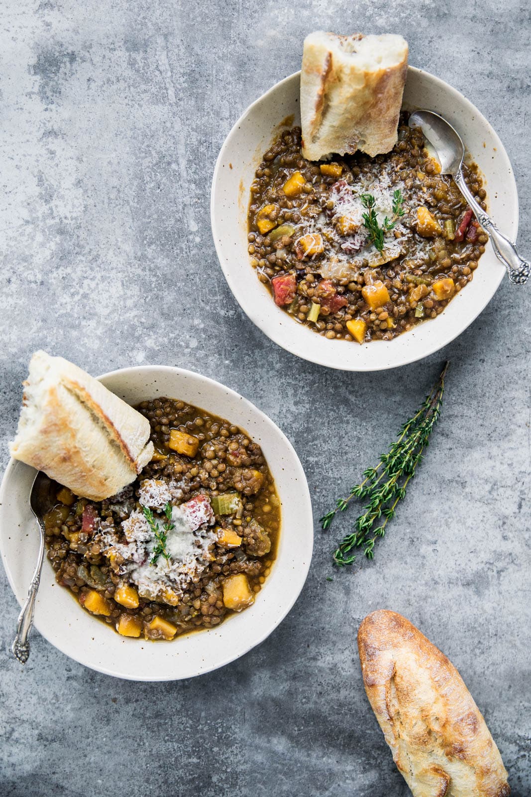 two bowls of butternut squash lentil stew with pieces of bread
