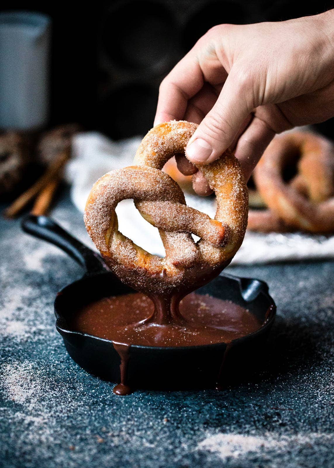 dipping a cinnamon sugar pretzel into hot fudge sauce