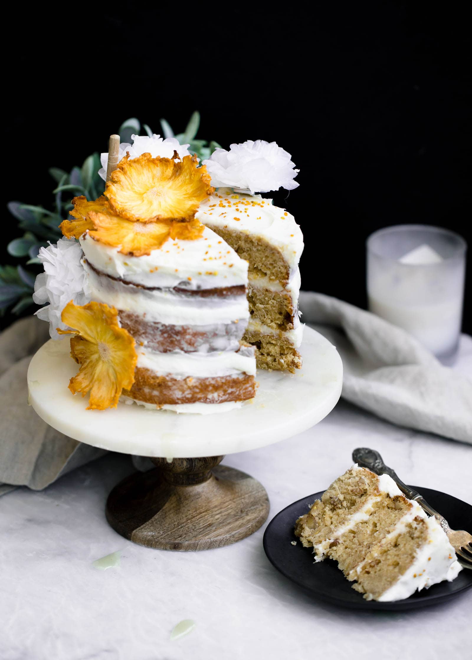 Hummingbird Cake slice on a plate next to cake stand