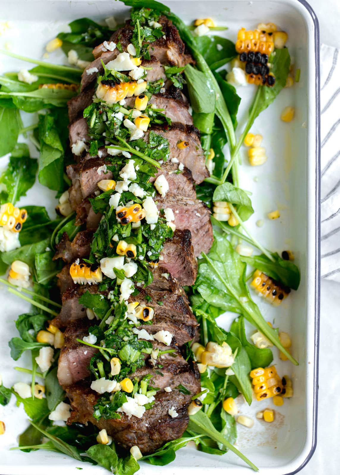An epic Chimichurri Steak Salad with charred corn, cotija cheese, arugula, and a homemade chimichurri sauce. Perfect for summer nights!