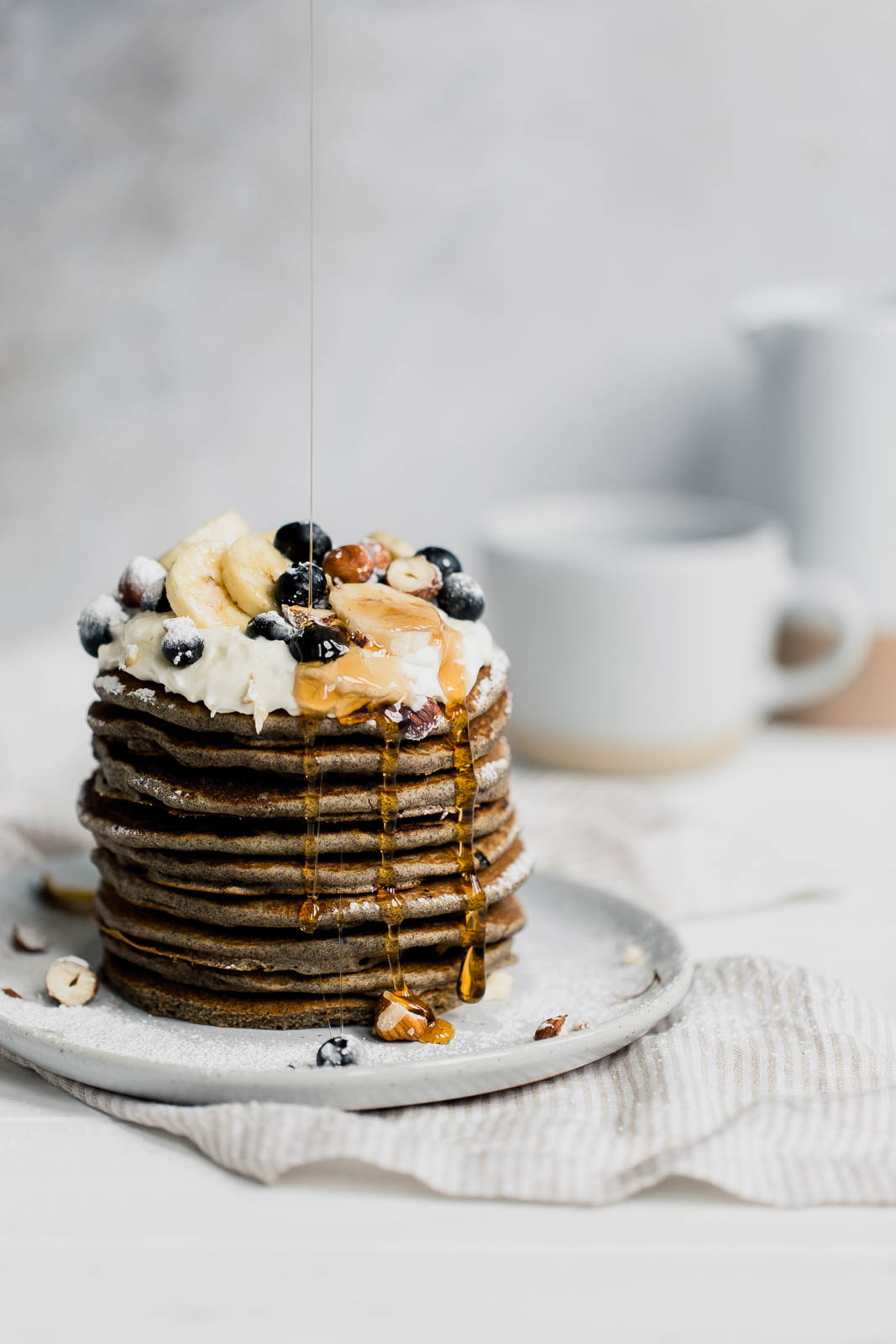 drizzling maple syrup onto gluten free buckwheat pancakes