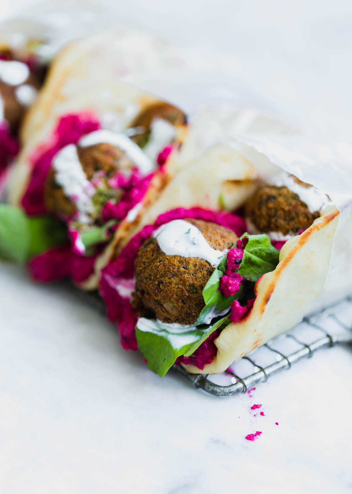 green falafel sandwiches topped with beet hummus and yogurt