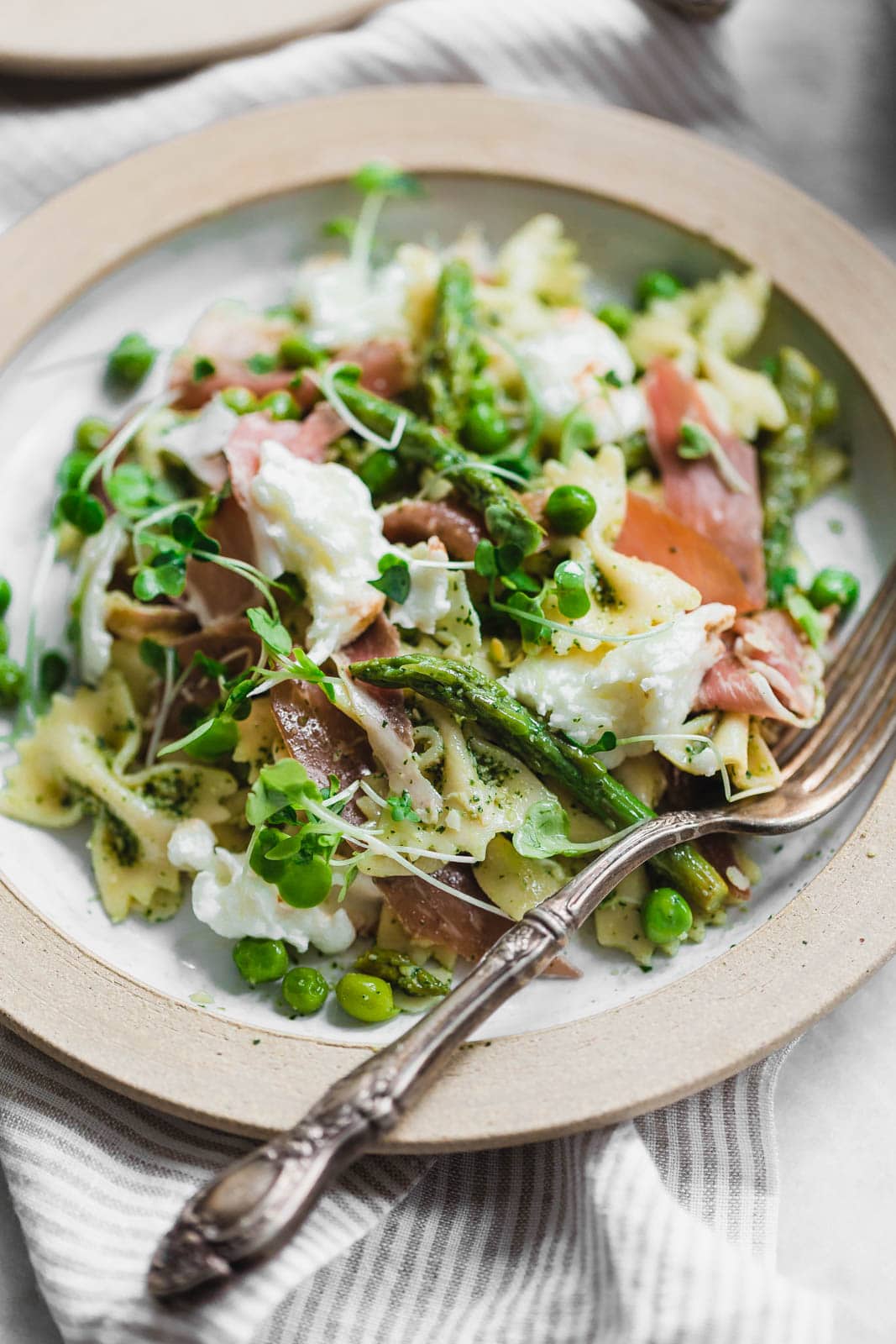A sensational pasta salad with homemade pesto, prosciutto, peas, asparagus, and burrata.