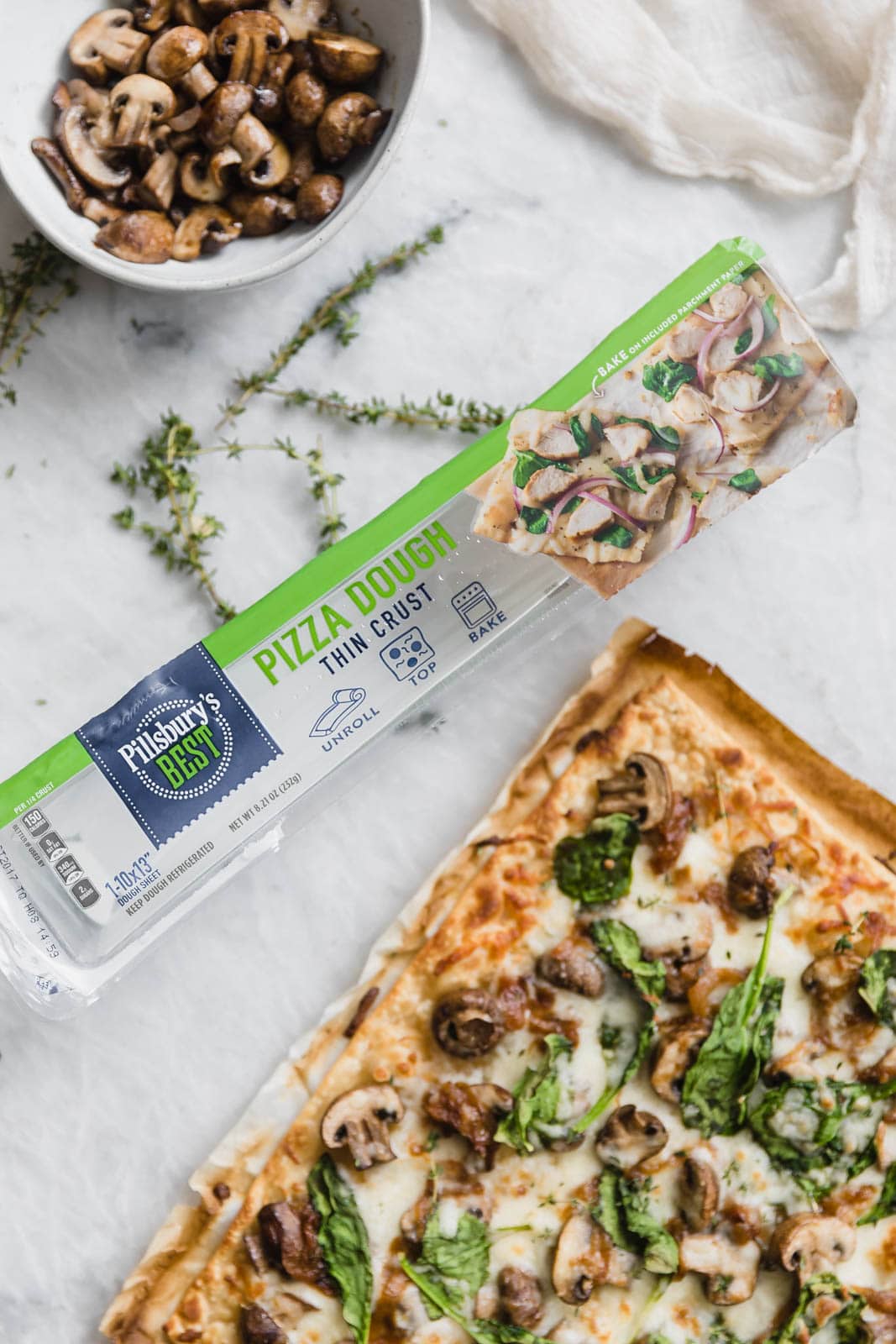 Caramelized Onion, Mushroom, & Spinach Pizza next to dough