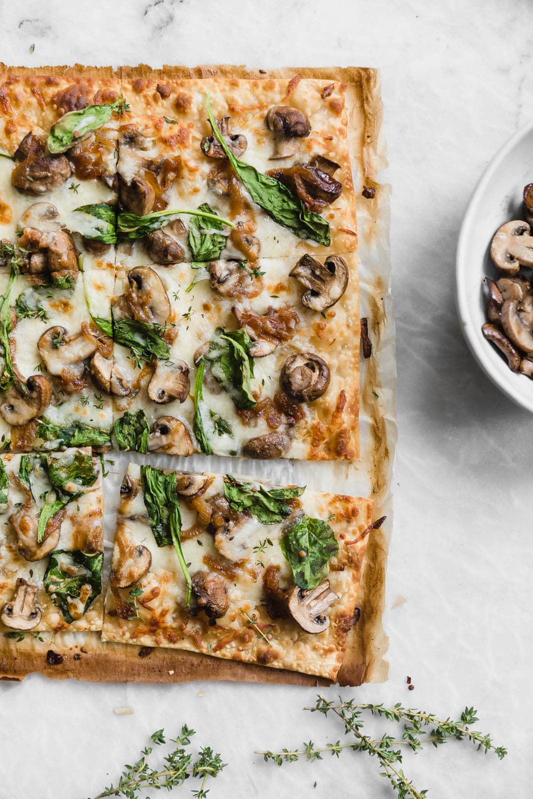Caramelized Onion, Mushroom, & Spinach Pizza on marble countertop