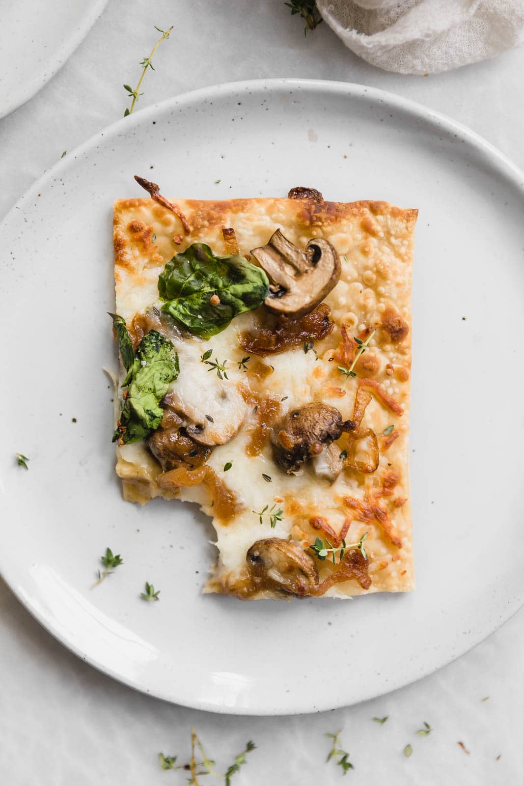 Caramelized Onion, Mushroom, & Spinach Pizza slice on a plate