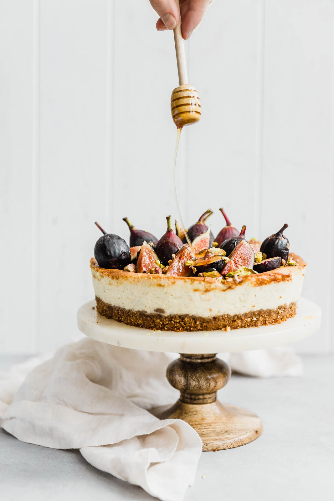 Vanilla bean cheesecake being drizzled with honey