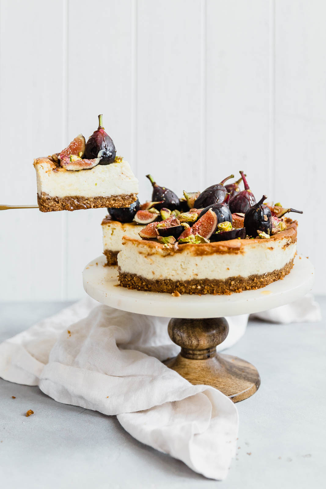 Vanilla bean cheesecake being sliced on a cake stand