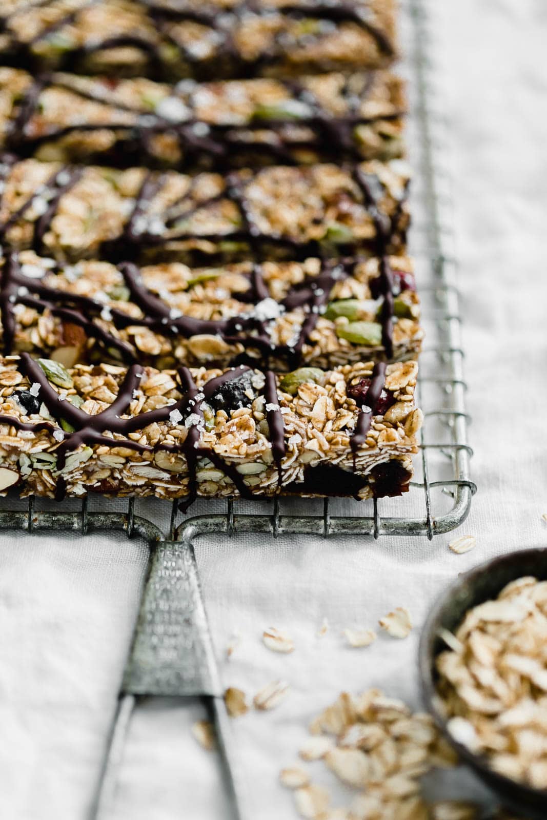 Raw Seedy Granola Bars made with oats, sunflower seeds, pepitas, sesame seeds, almonds, apricots, and honey, topped with a drizzle of dark chocolate