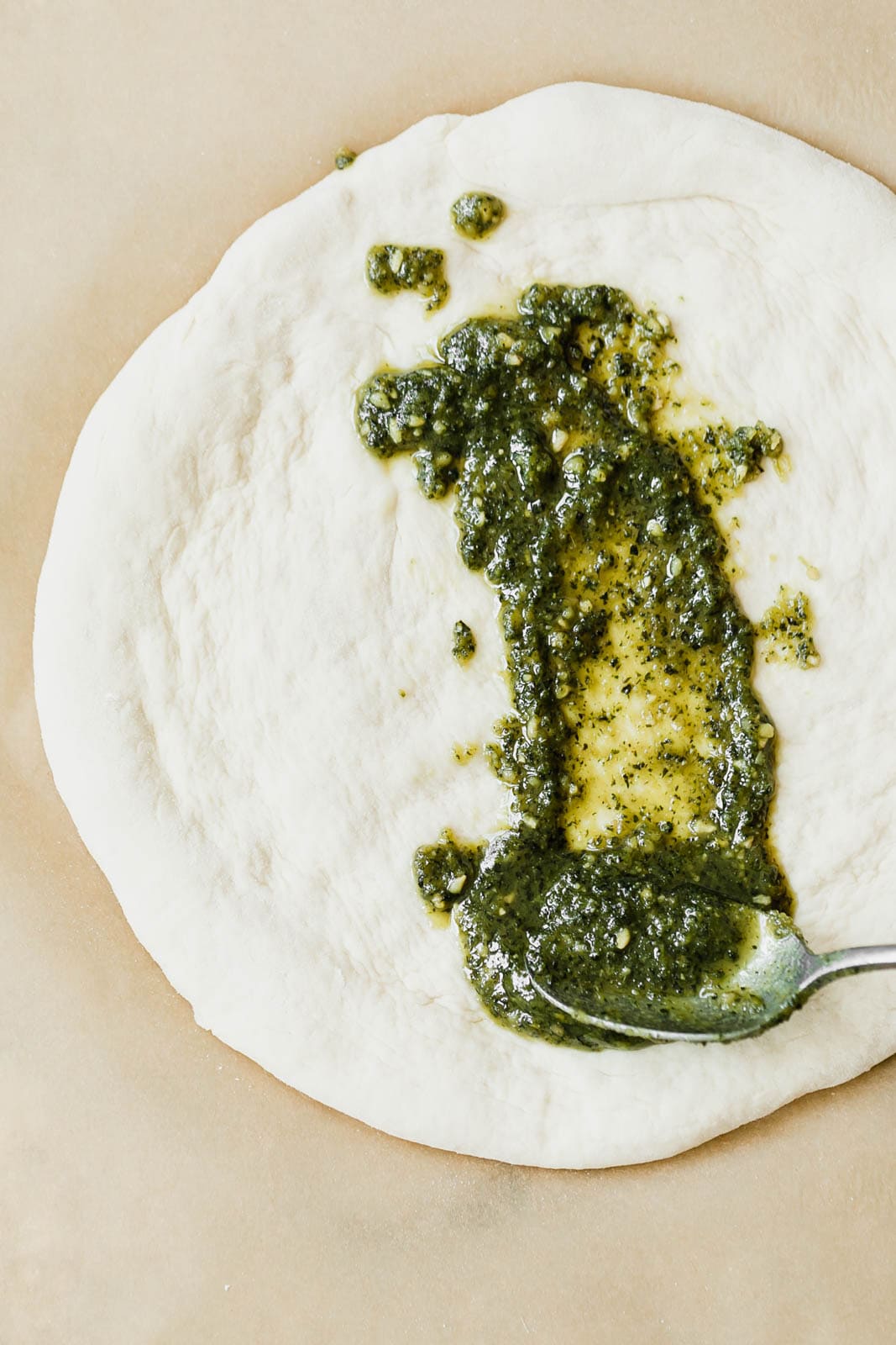 A Spring Green Goddess Pizza made with pesto, zucchini, spring peas, watercress, mozzarella, and a green goddess dressing.