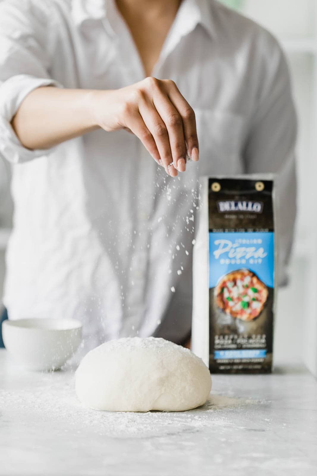 A Spring Green Goddess Pizza made with pesto, zucchini, spring peas, watercress, mozzarella, and a green goddess dressing.