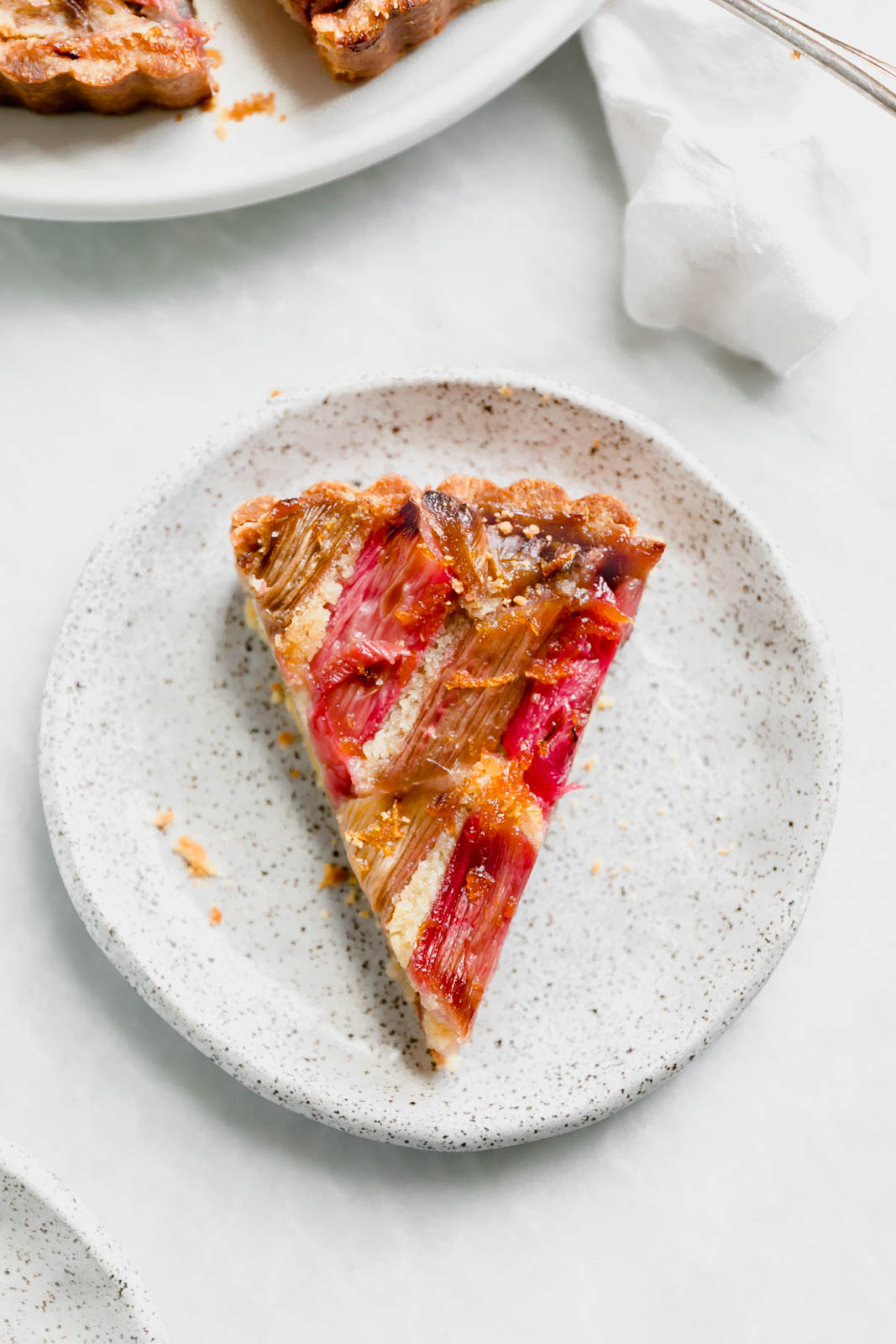 The most showstopping Rhubarb Bakewell Tart made with a pâte sucrée crust, strawberry preserves, almond frangipane, and an orange-soaked rhubarb top