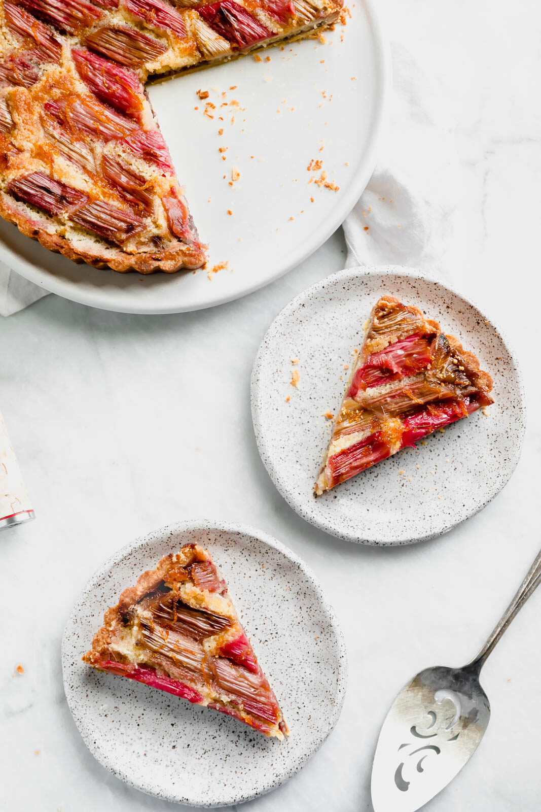 The most showstopping Rhubarb Bakewell Tart made with a pâte sucrée crust, strawberry preserves, almond frangipane, and an orange-soaked rhubarb top