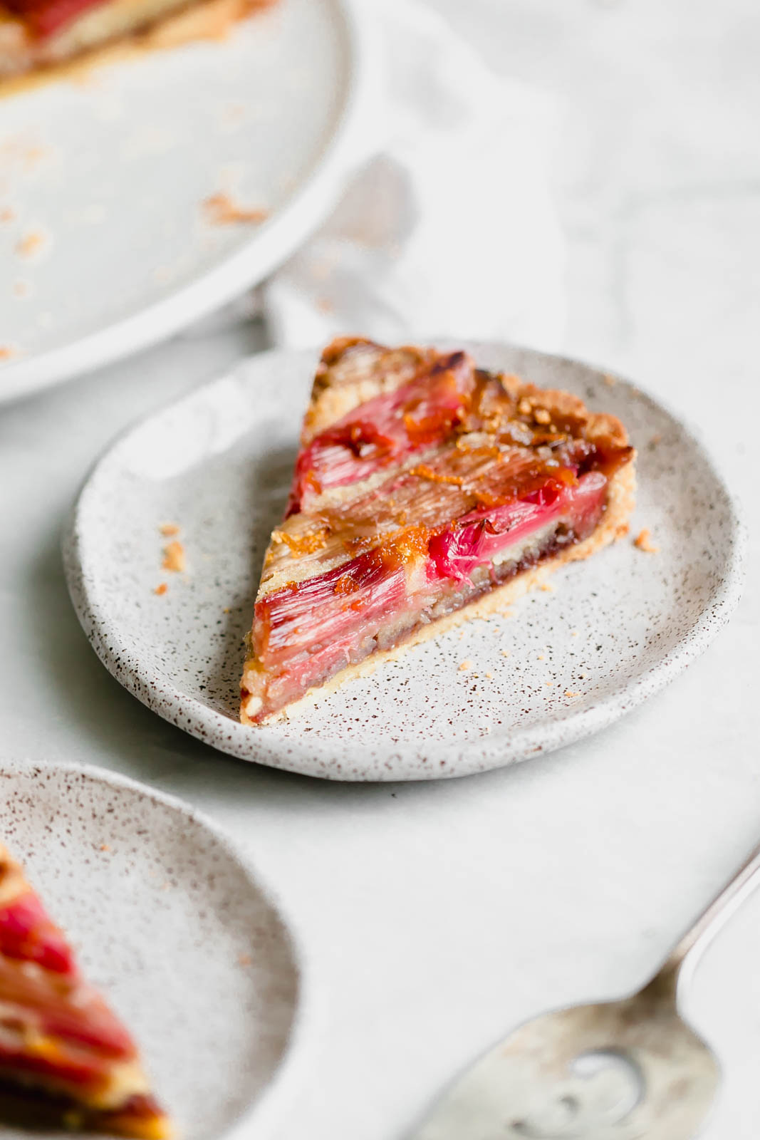 The most showstopping Rhubarb Bakewell Tart made with a pâte sucrée crust, strawberry preserves, almond frangipane, and an orange-soaked rhubarb top