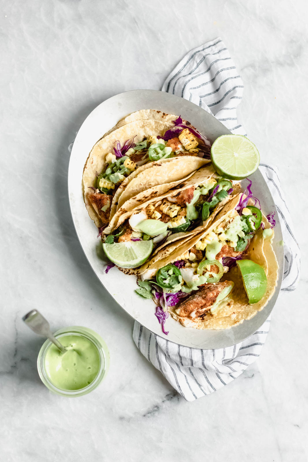 My go-to recipe for Taco Tuesday fish tacos: flakey blackened fish, cabbage, charred corn, jalapeños, and a “creamy” dairy-free avocado cilantro crema!