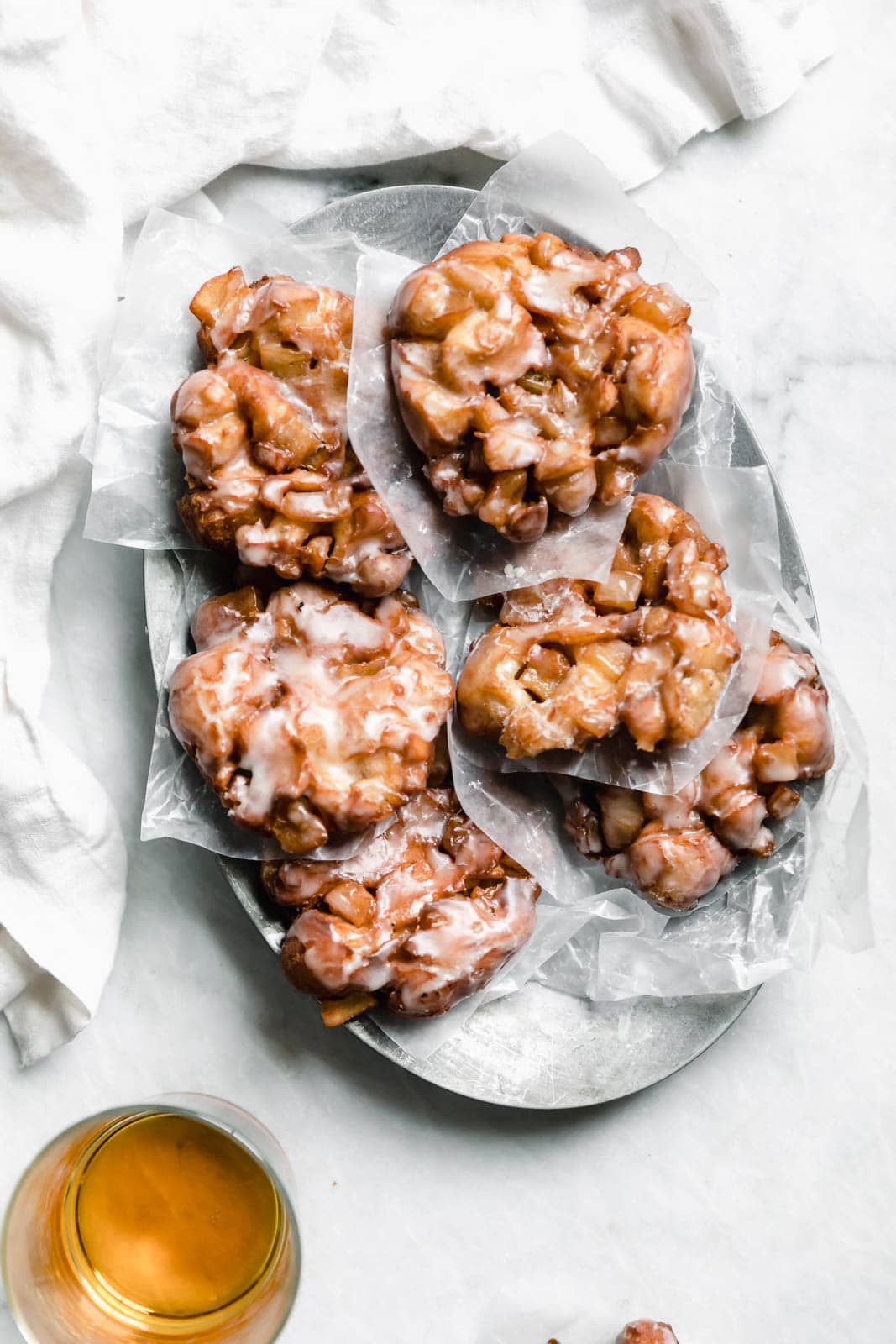 bourbon apple fritters on a platter with parchment paper