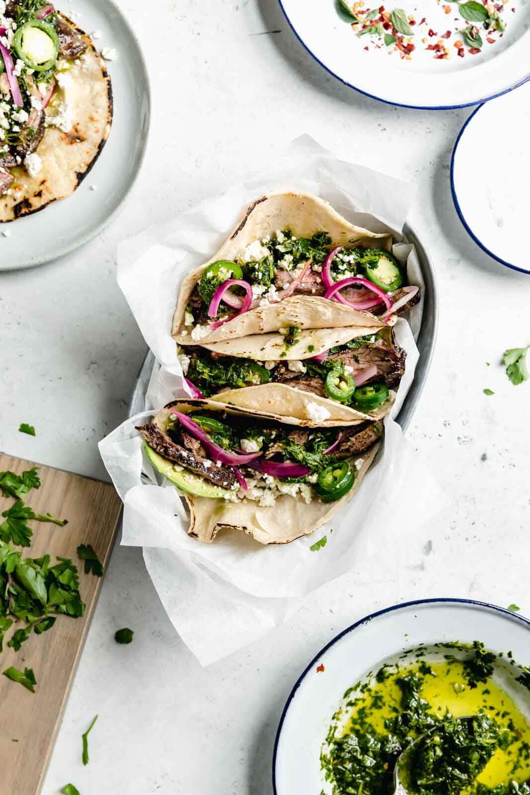 Introducing your new favorite weeknight meal: chimichurri steak tacos loaded with juicy flank steak, avocado, jalapeños, pickled onions and cotija. YUM.