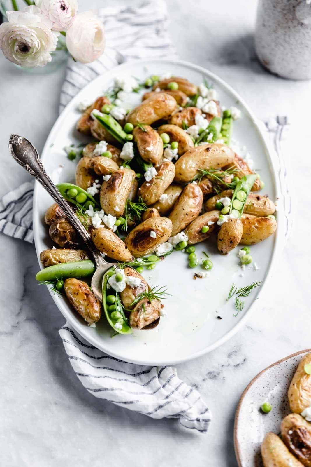 These roasted fingerling potatoes with dill, goat cheese, and peas are our new fav side dish. Full of texture and flavor, you'll love these spring potatoes.