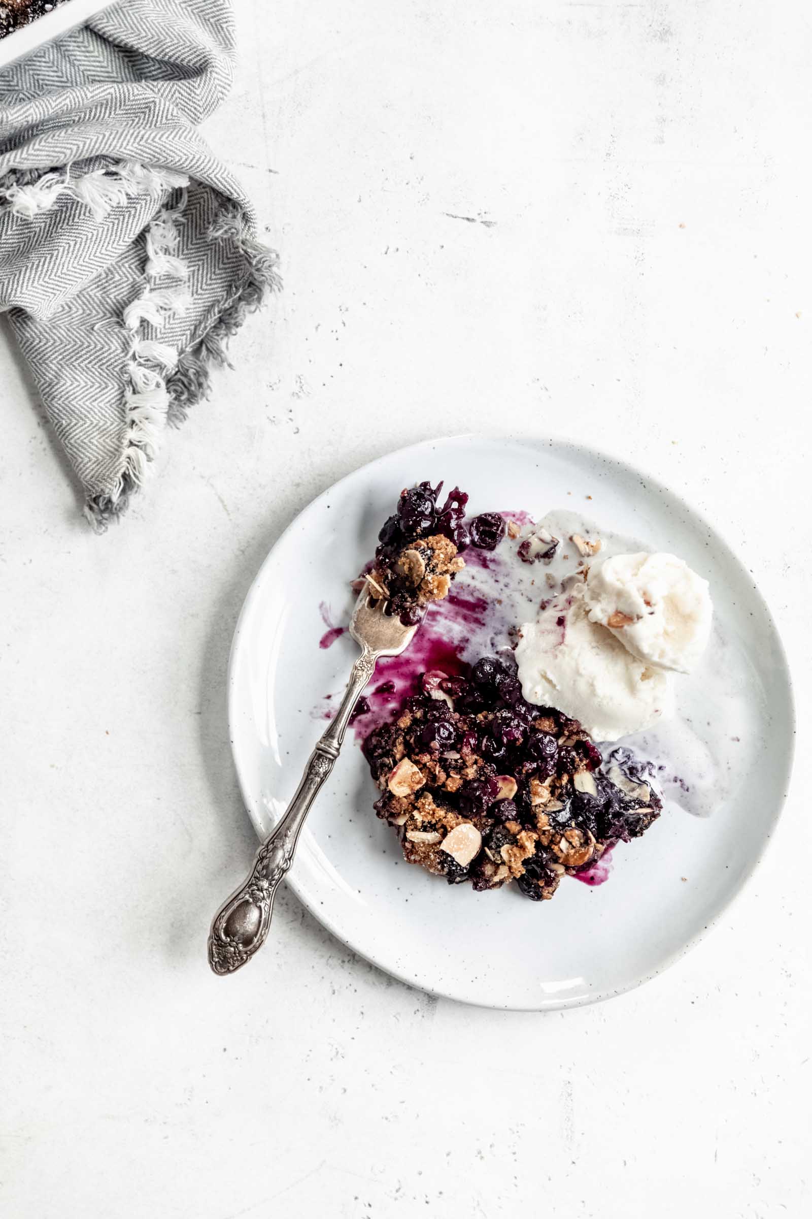 plate of vegan blueberry crisp with vanilla ice cream