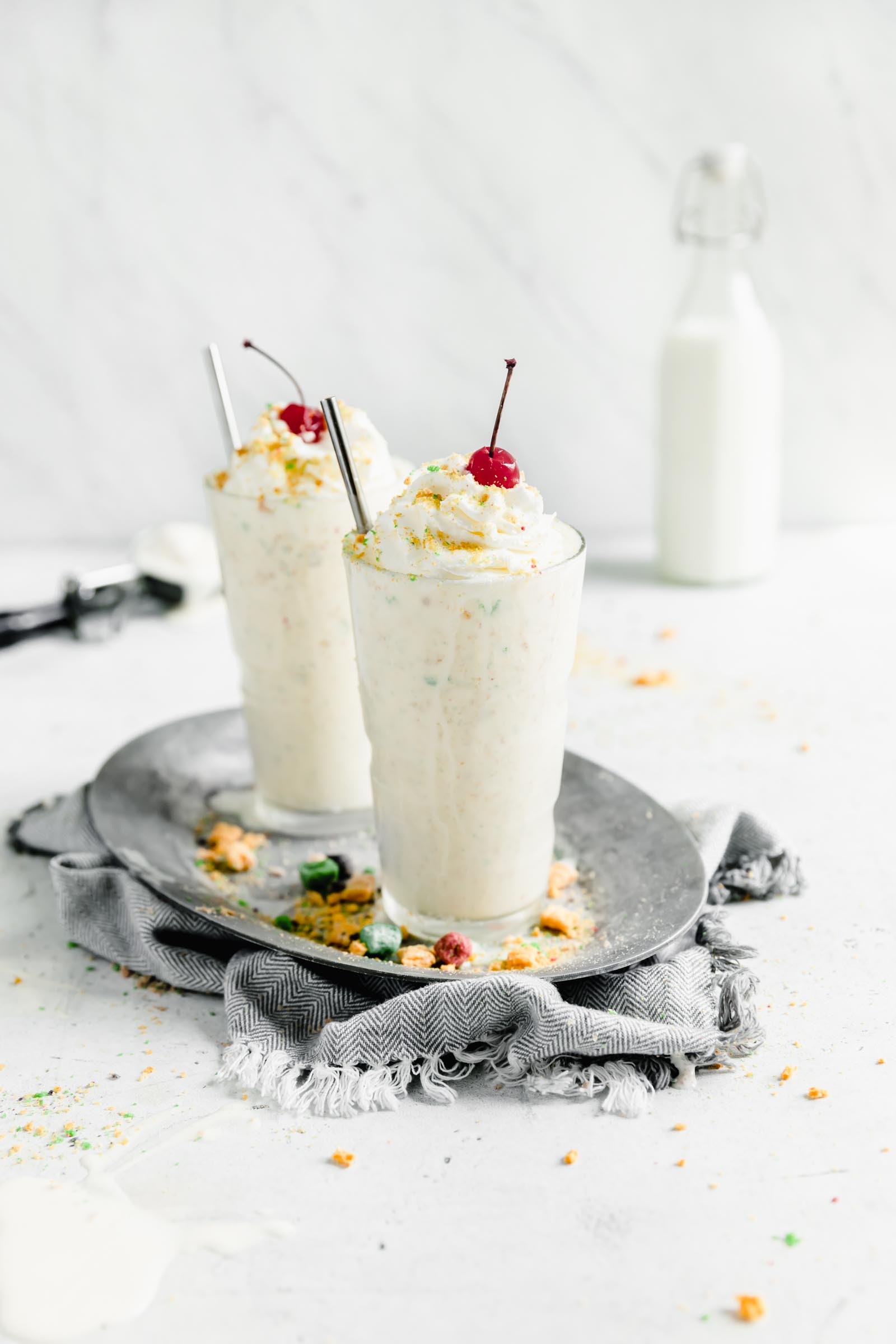 two captain crunch milkshakes topped with whipped cream and cherries