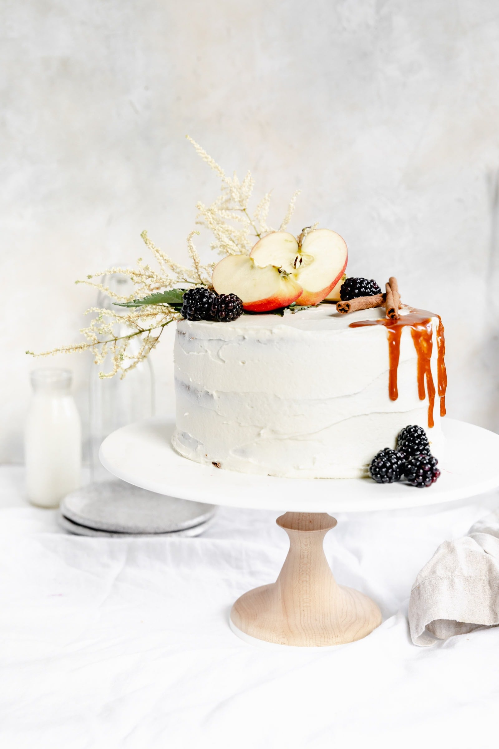 apple cake with cream cheese frosting and berries on a cake stand