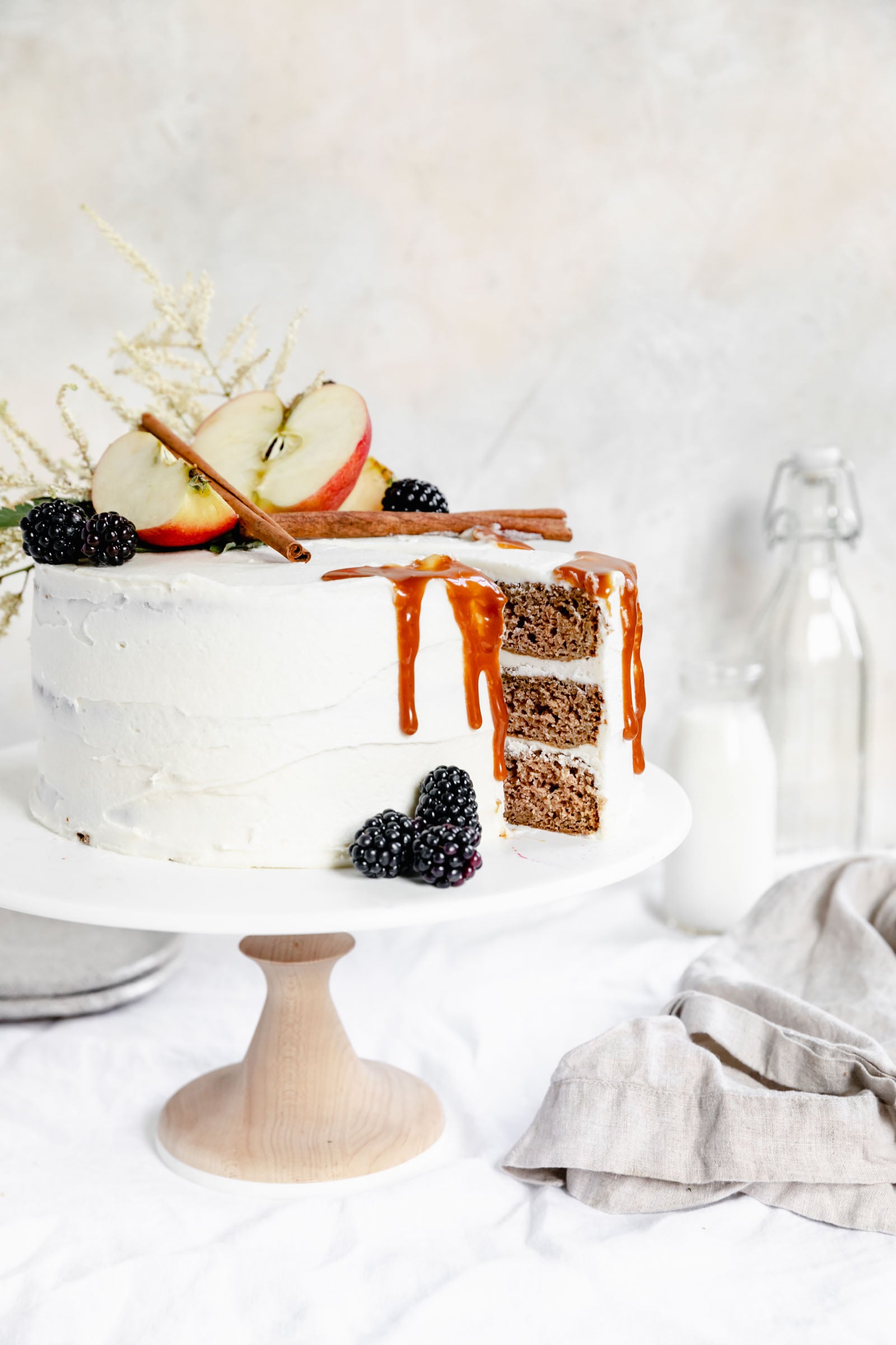caramel apple cake with a slice taken out on a cake stand