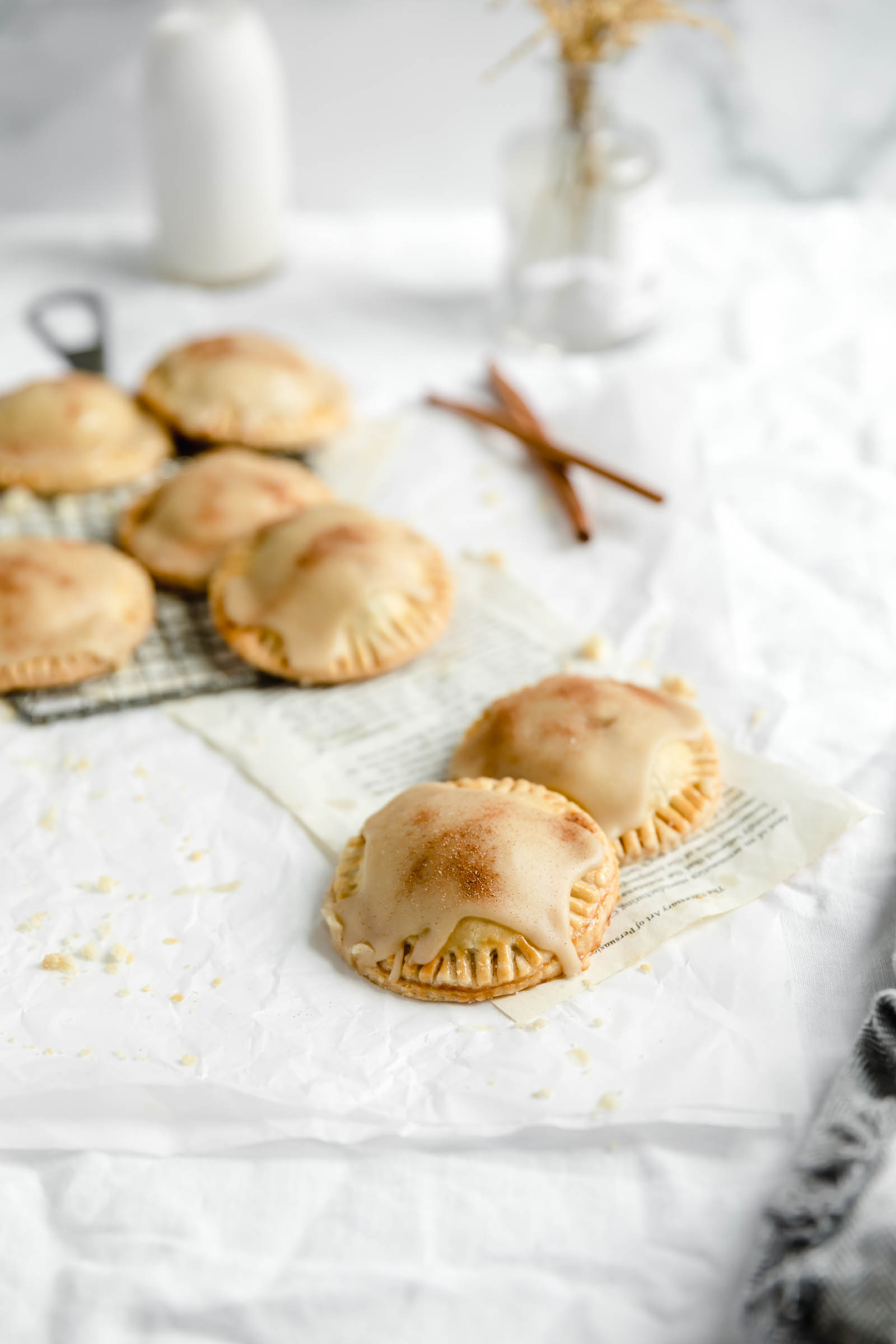 cinnamon apple hand pies on a cooling rack with two in the front on parchment paper