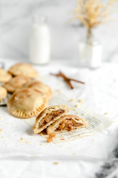 mini cinnamon apple pies cut open with cinnamon stick and a glass of milk