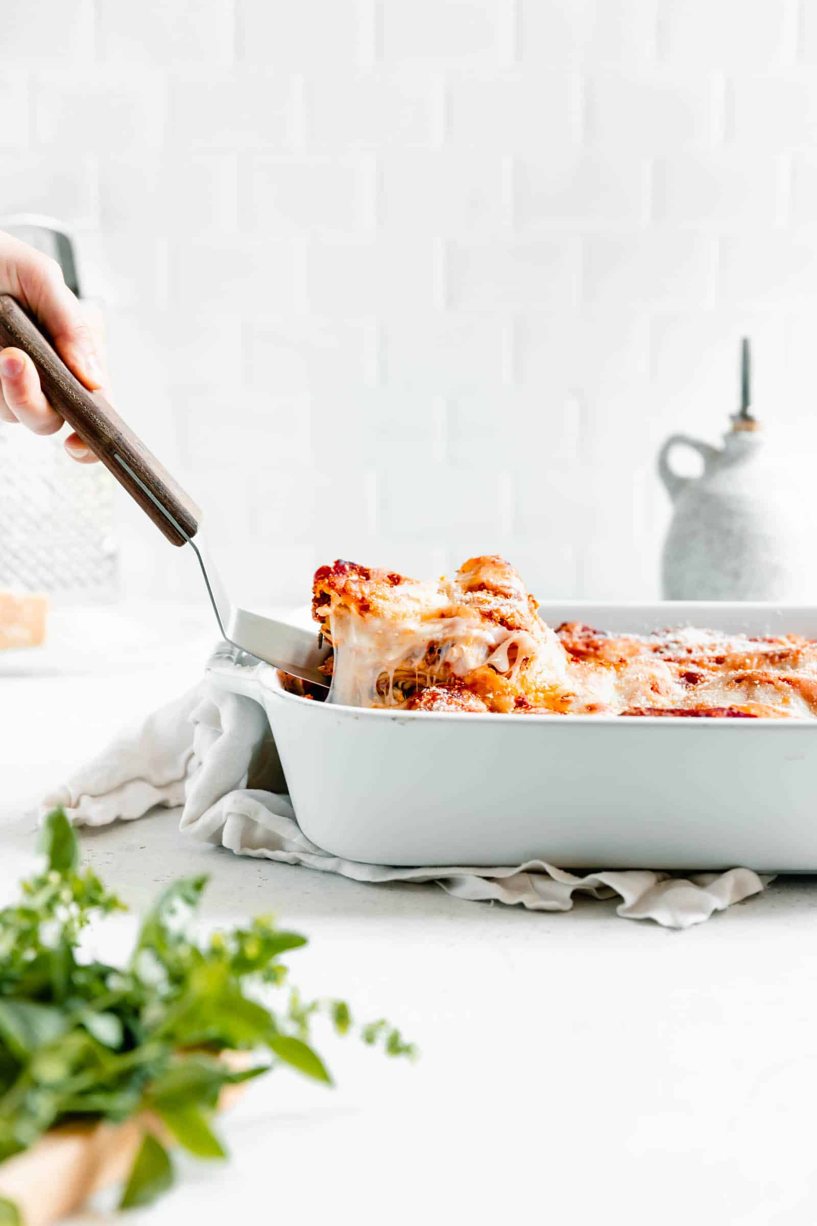 Classic homemade meat lasagna piece lifted out of pan with cheese pull