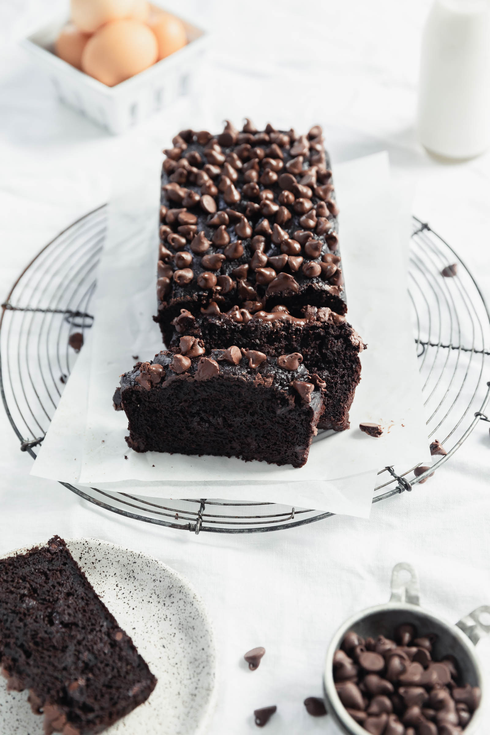 double chocolate zucchini bread topped with chocolate chips on a wire rack with parchment paper