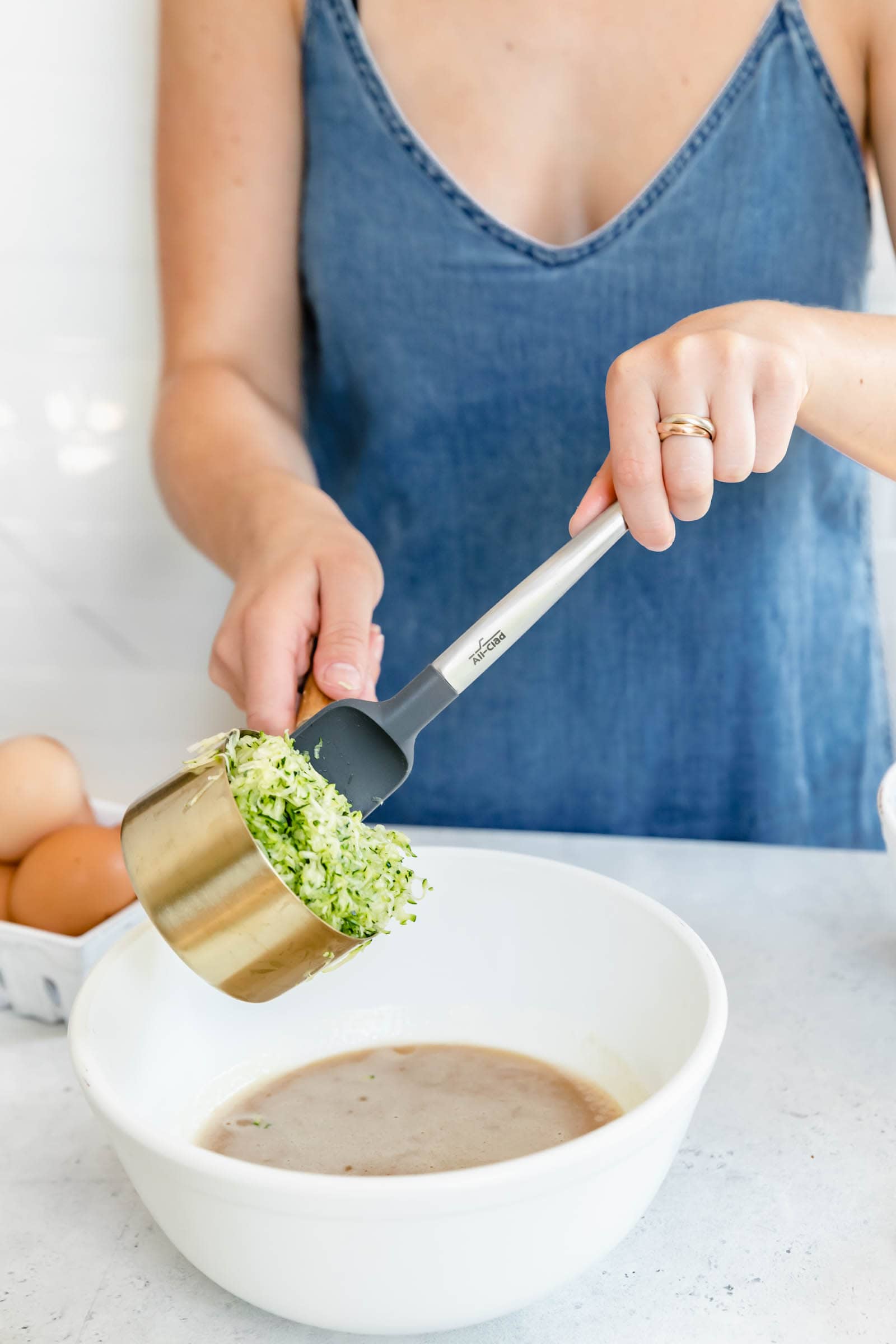 shredded zucchini going into bowl full of batter
