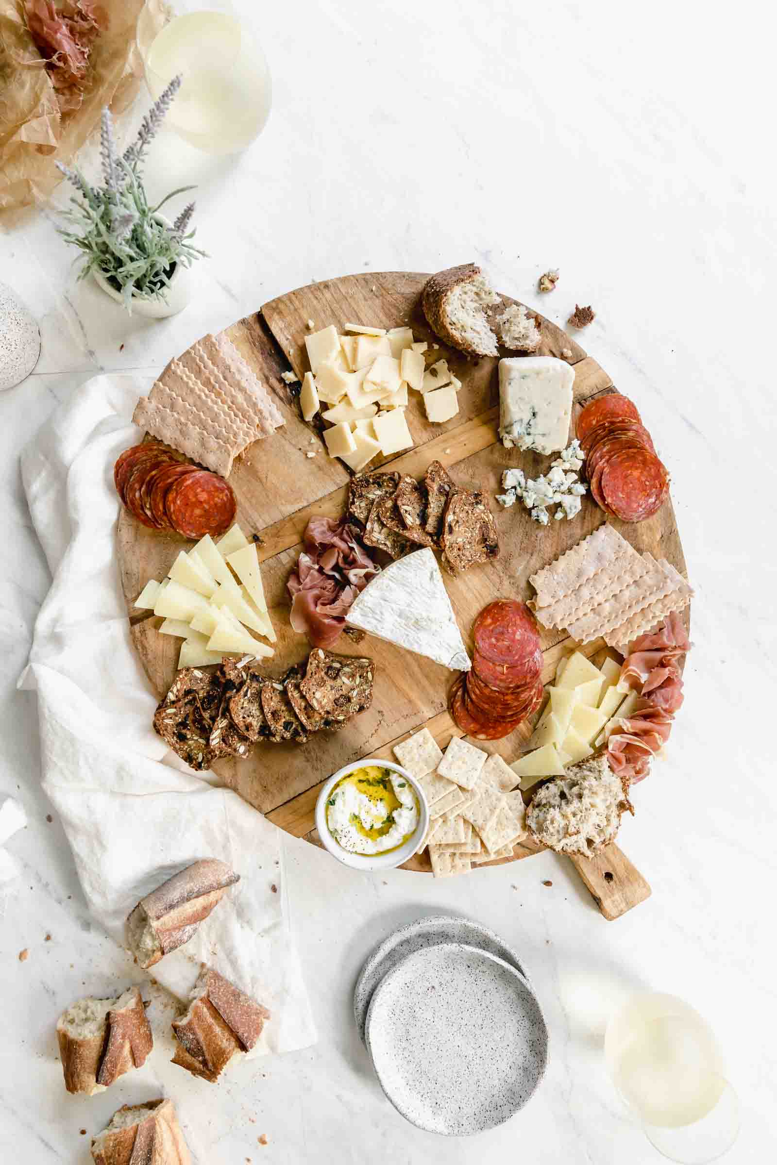 add variety of meats to cheese and and crackers on wooden board