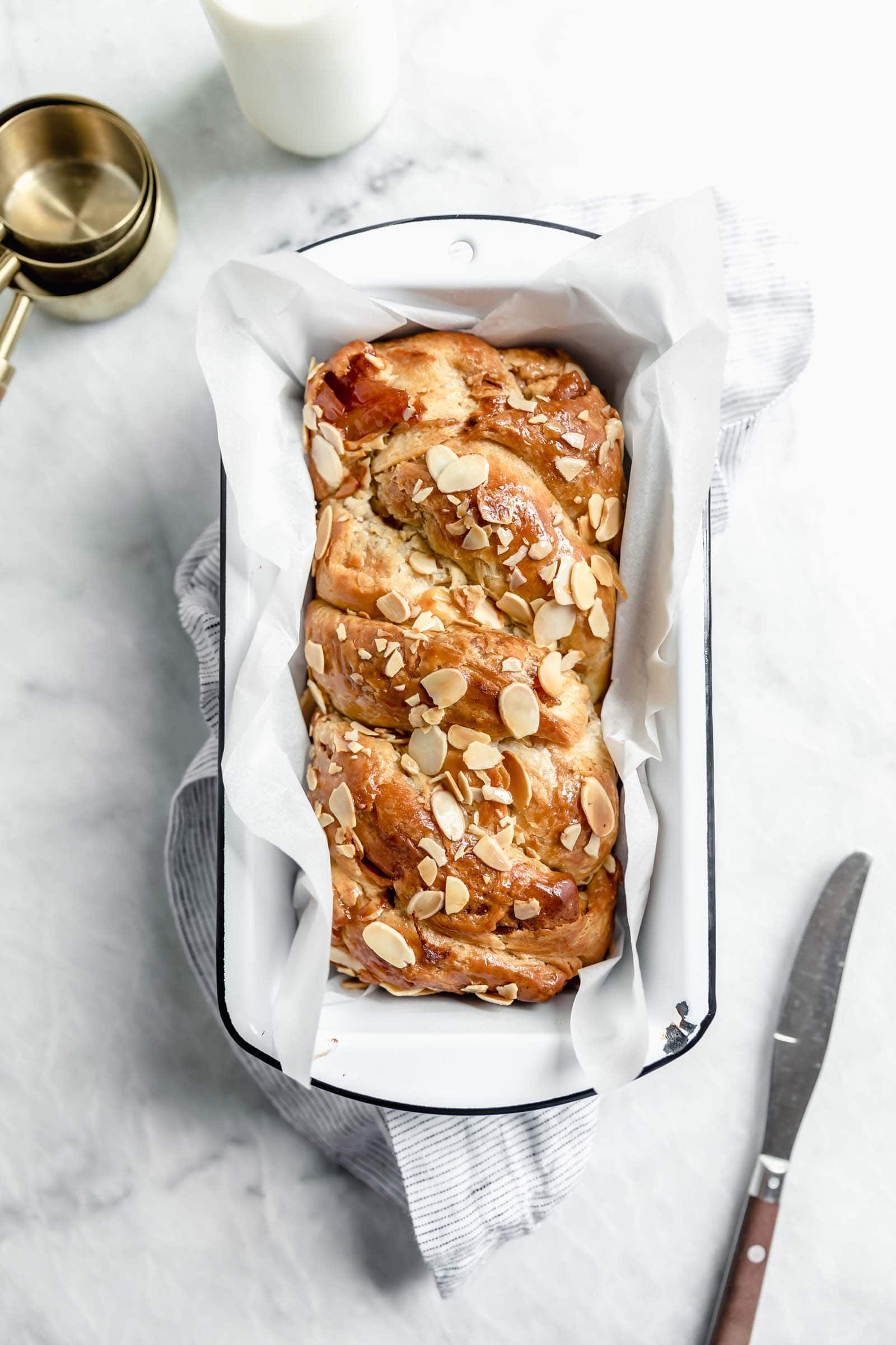 overhead shot of cinnamon apple babka in enamel pan topped with toasted almonds
