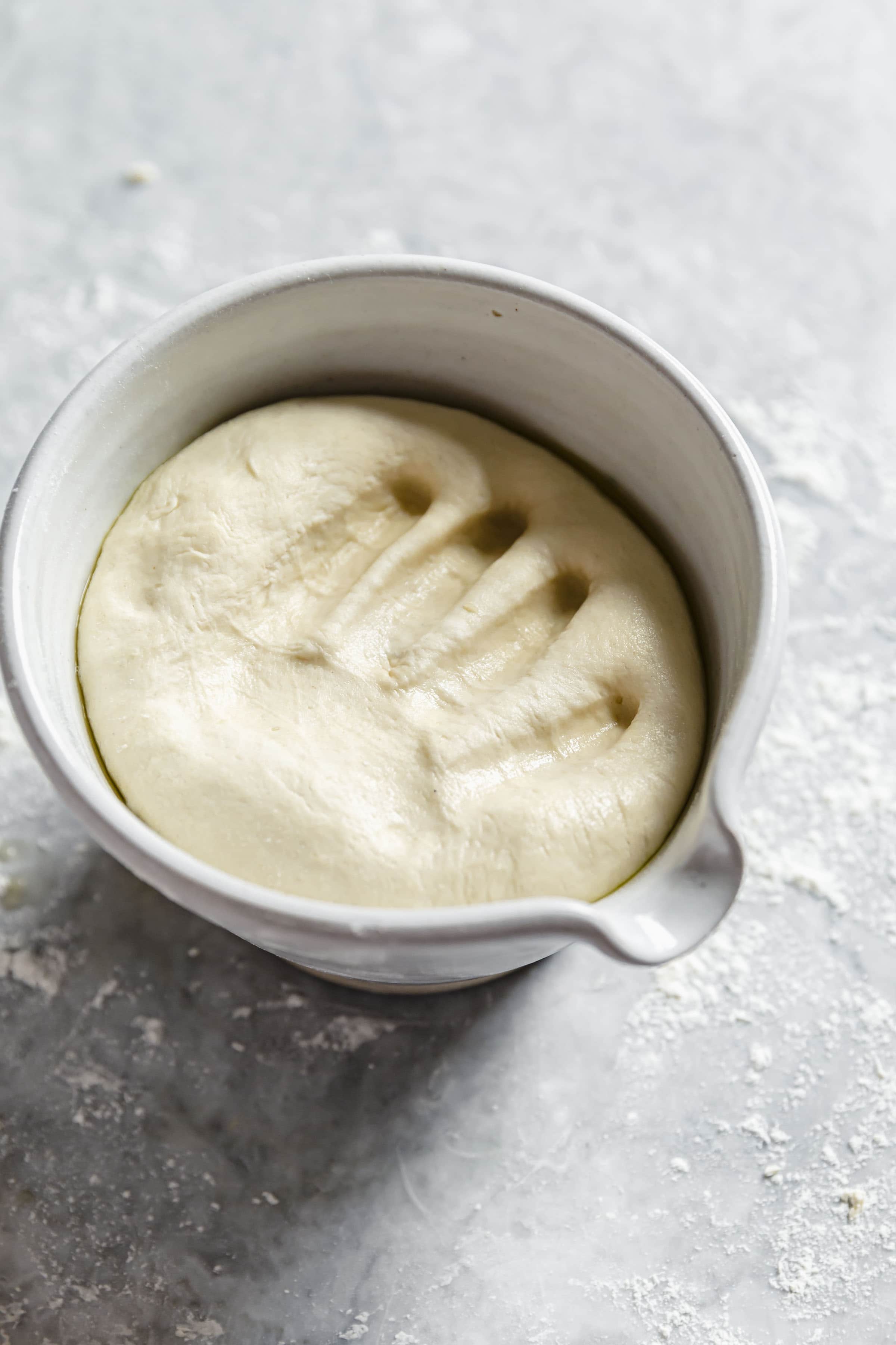 risen pizza dough dough in ceramic bowl