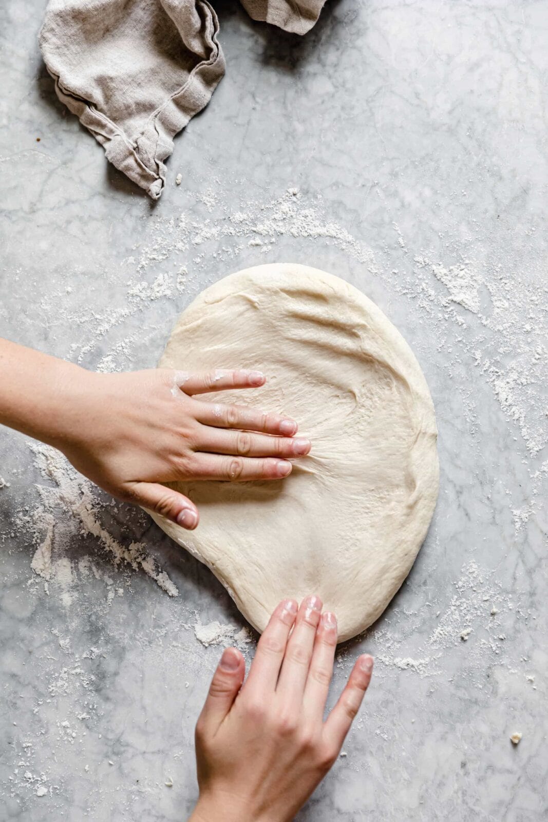 30 minute pizza dough stretched out on marble counter