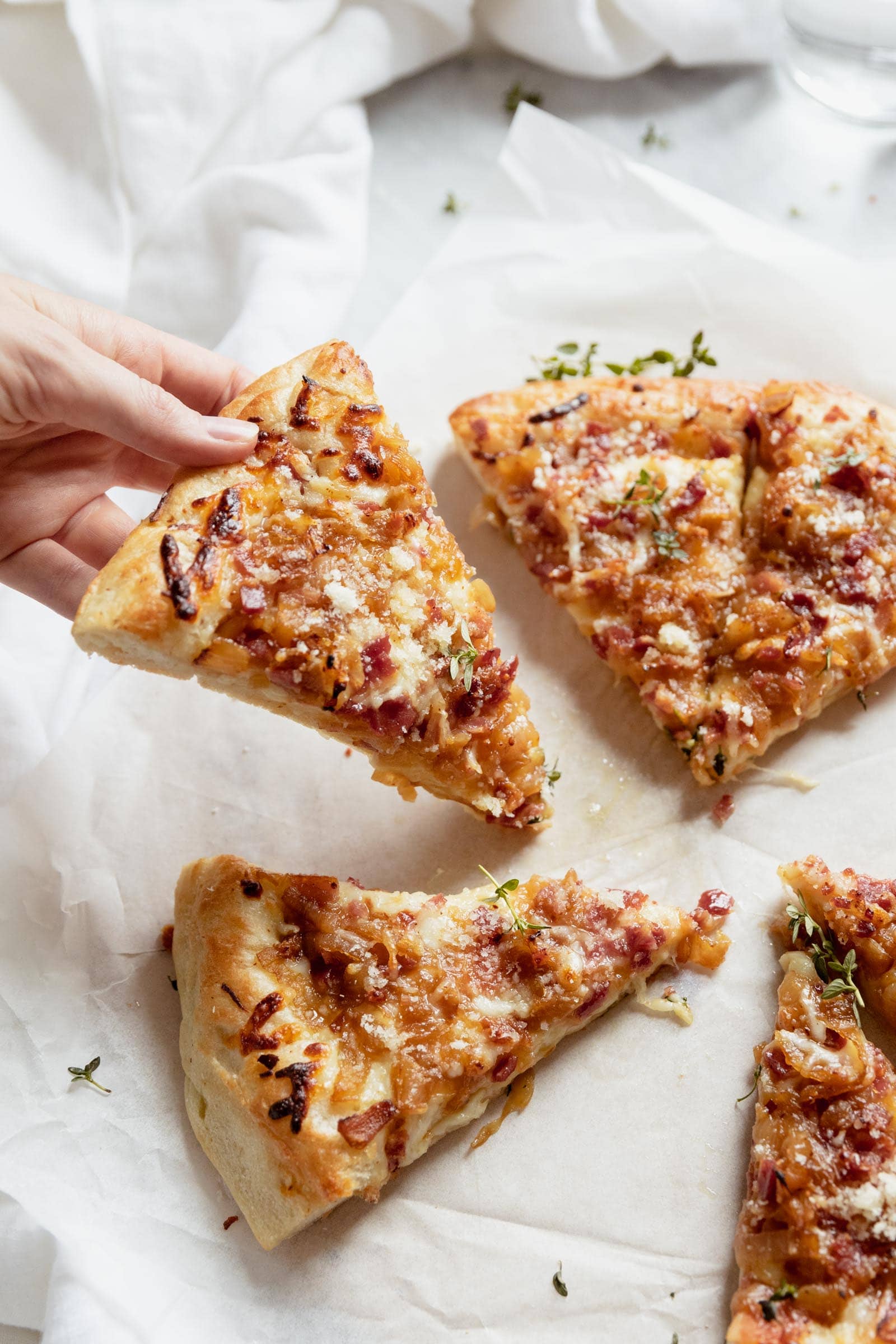 slice of caramelized onion and bacon pizza being picked up