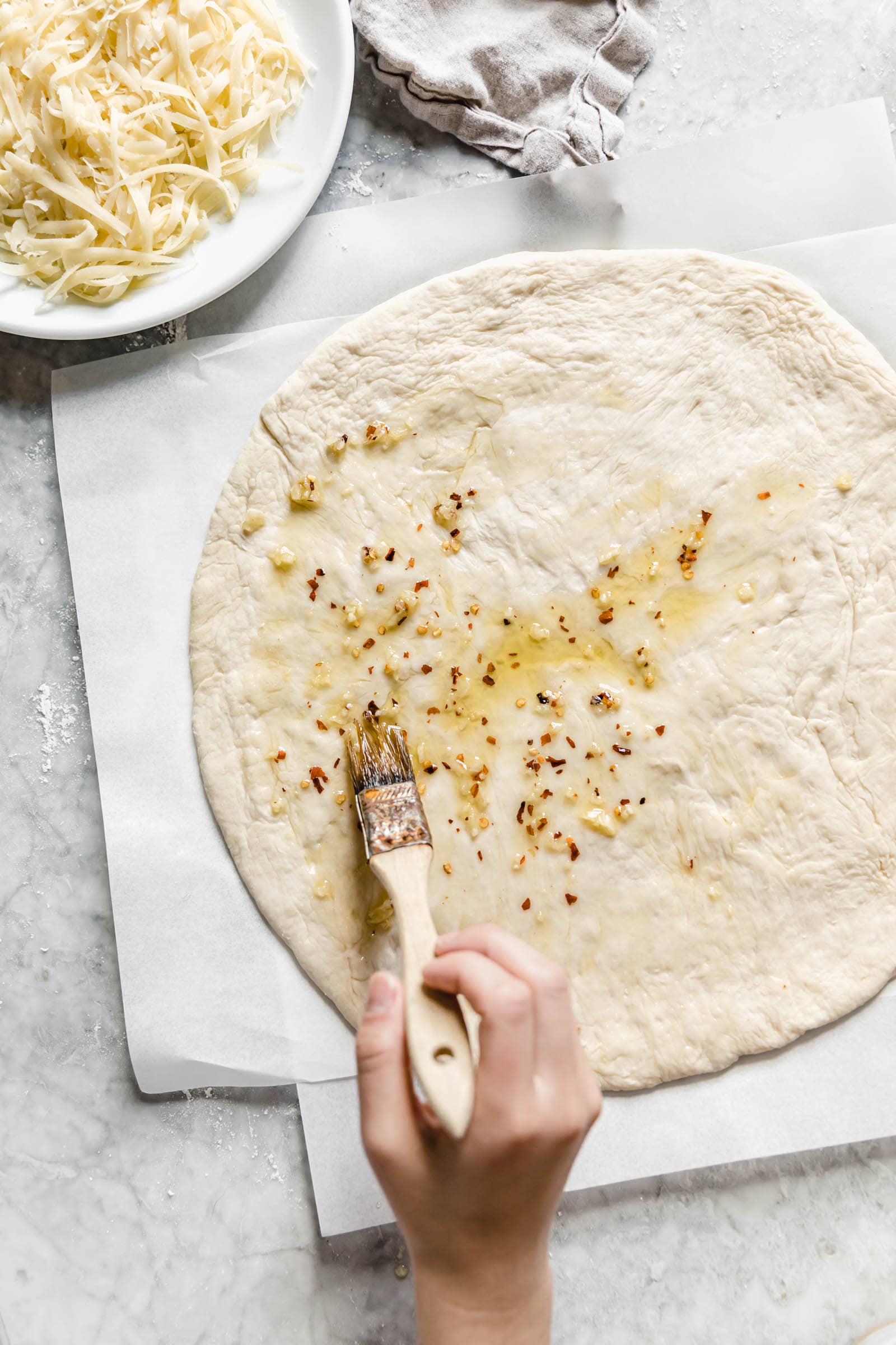 brush pizza dough with olive oil, minced garlic, and red pepper flakes using a pastry crust