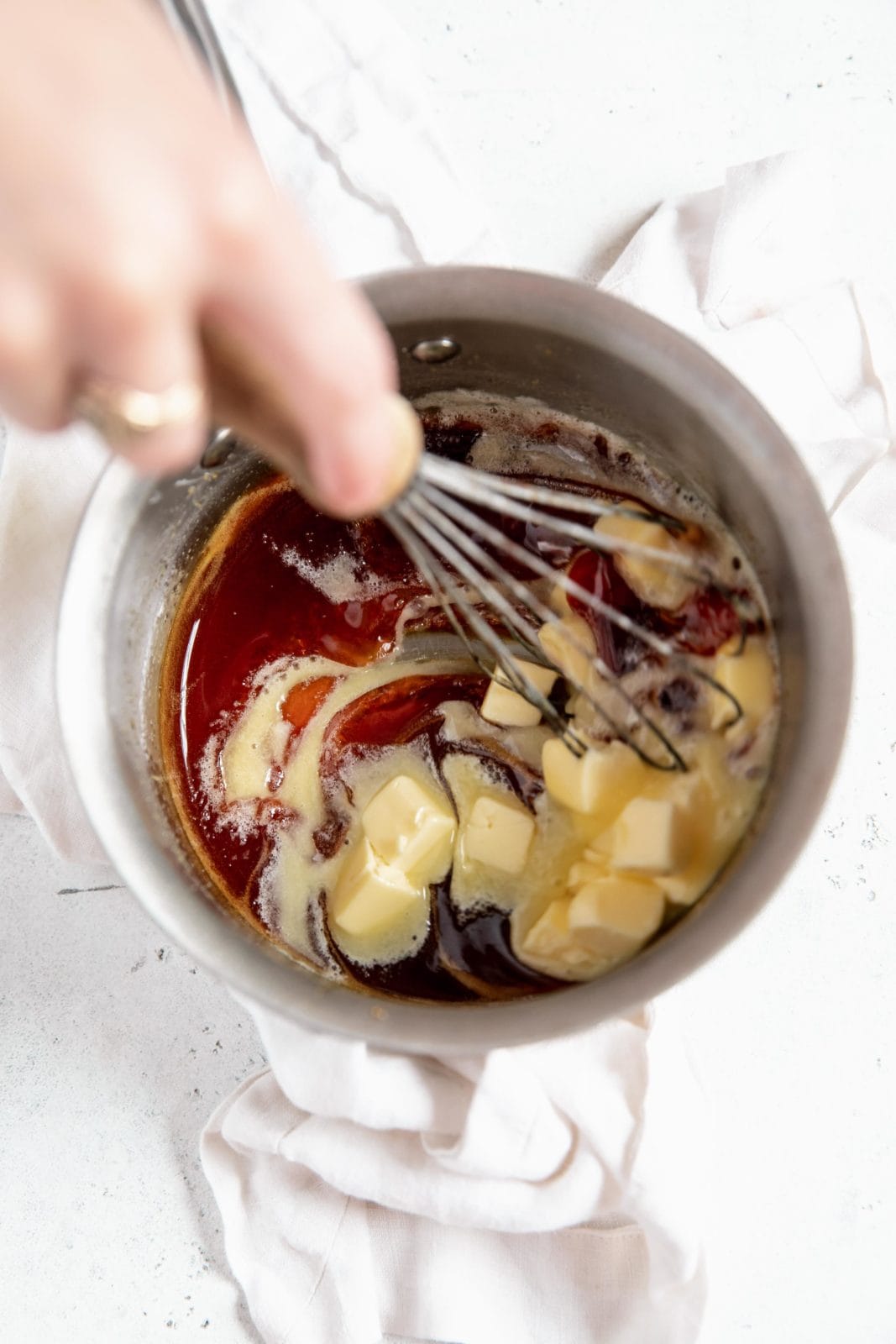 butter being stirred into easy homemade caramel sauce