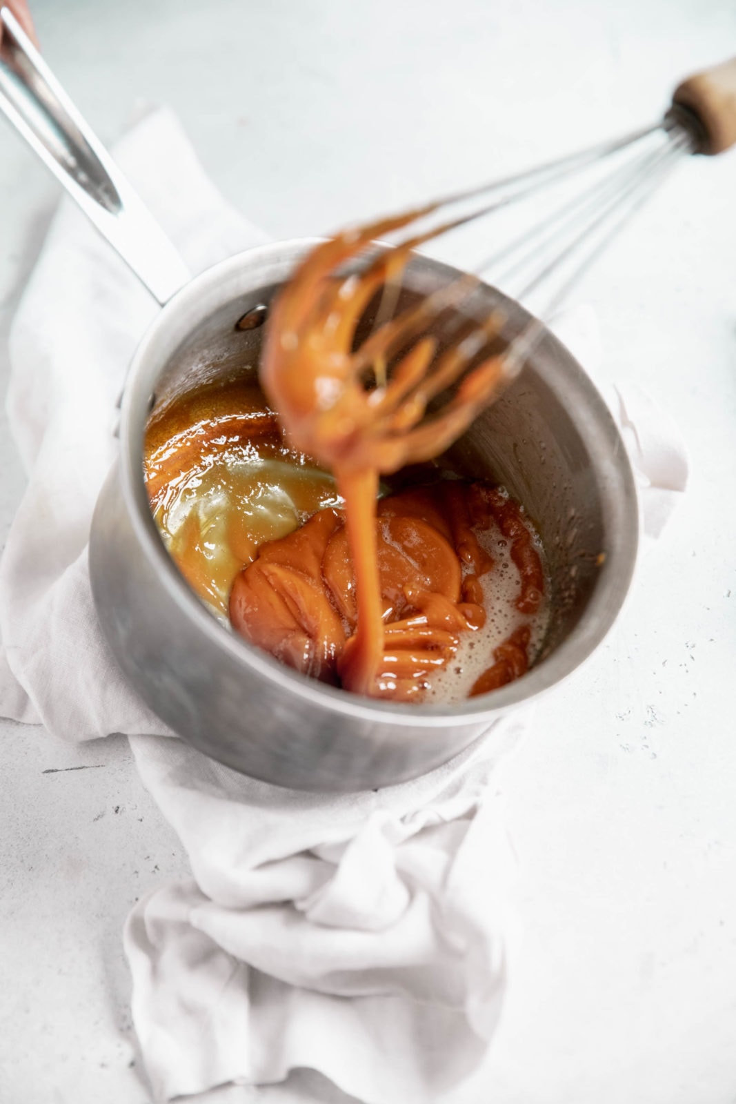 butter being stirred into easy homemade caramel sauce
