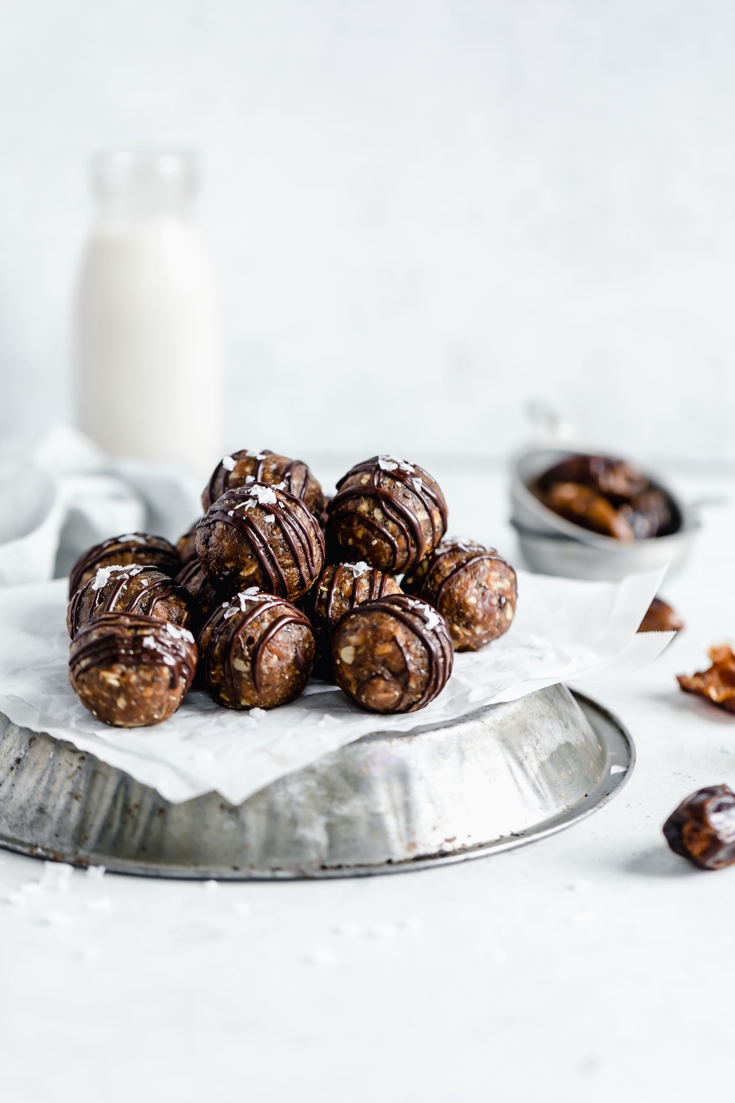 peanut butter oat energy bites on a pie tin with a glass of milk behind