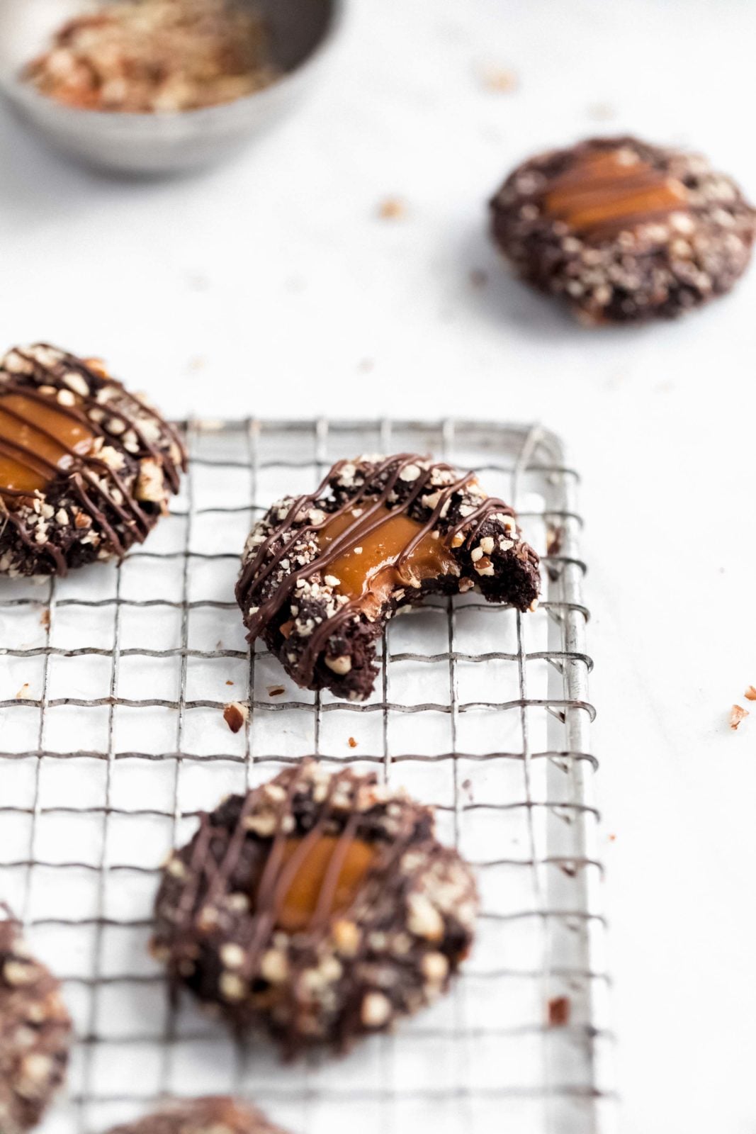 turtle thumbrints on a wire rack with bowl of chopped pecans