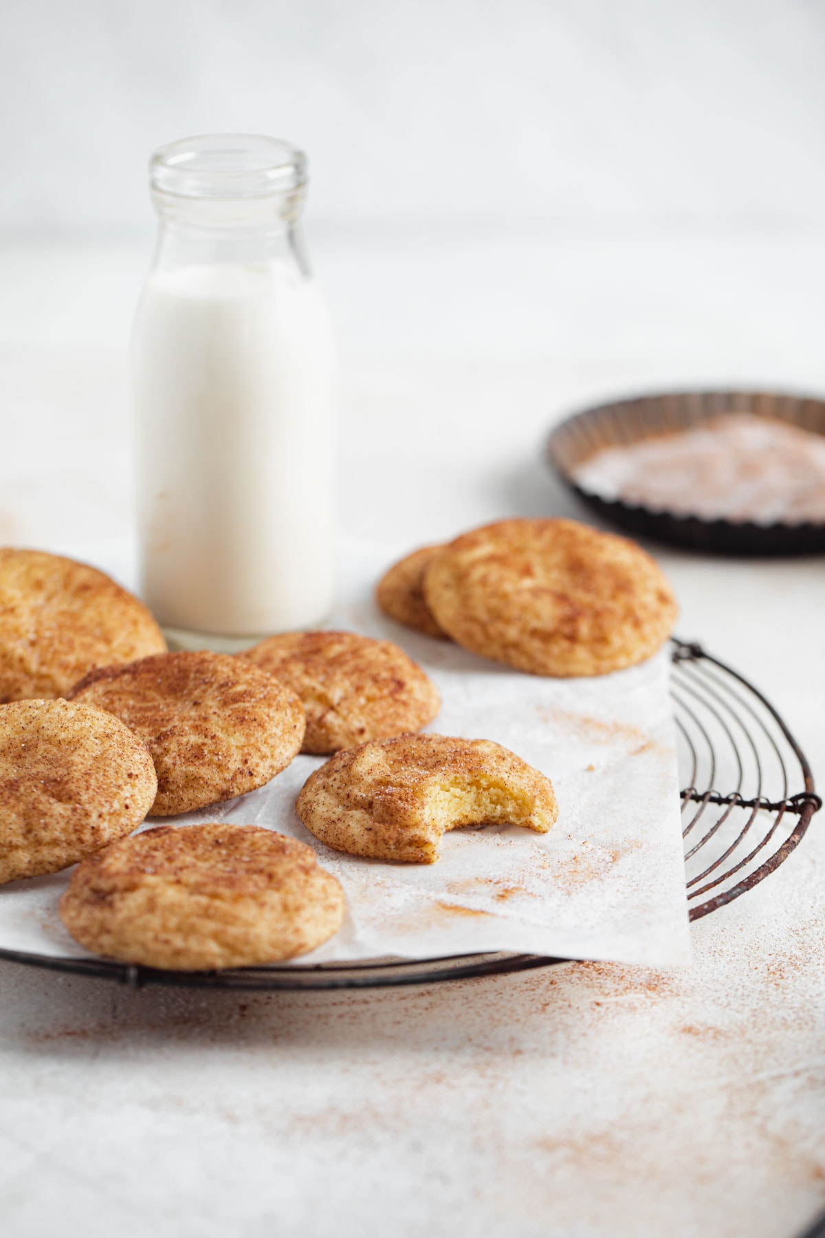 snickerdoodles on a cooling rack with a glass of milk