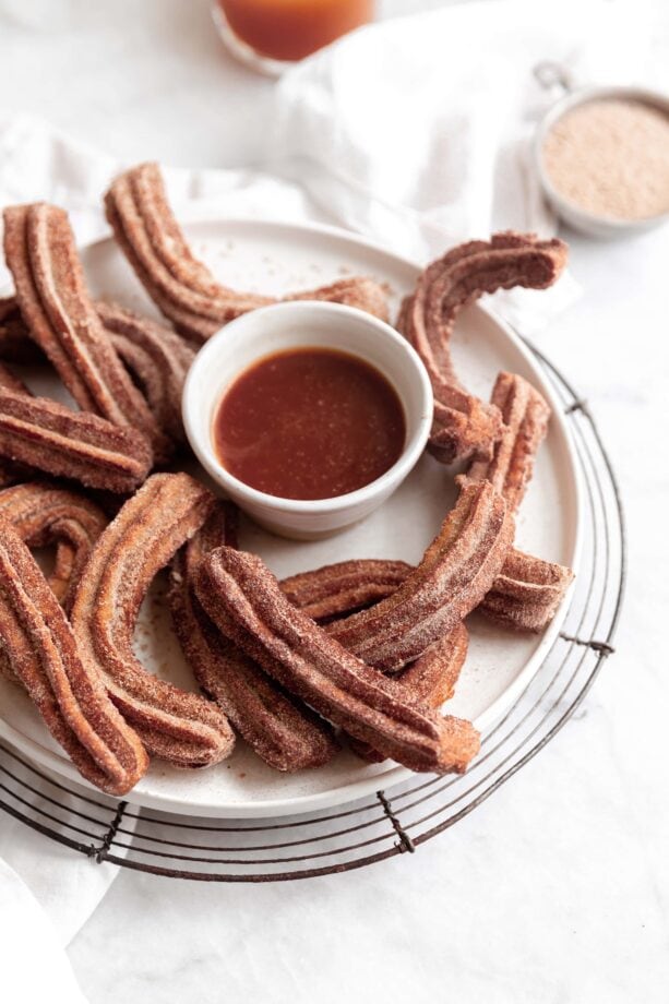 apple cider churros on a plate with caramel sauce