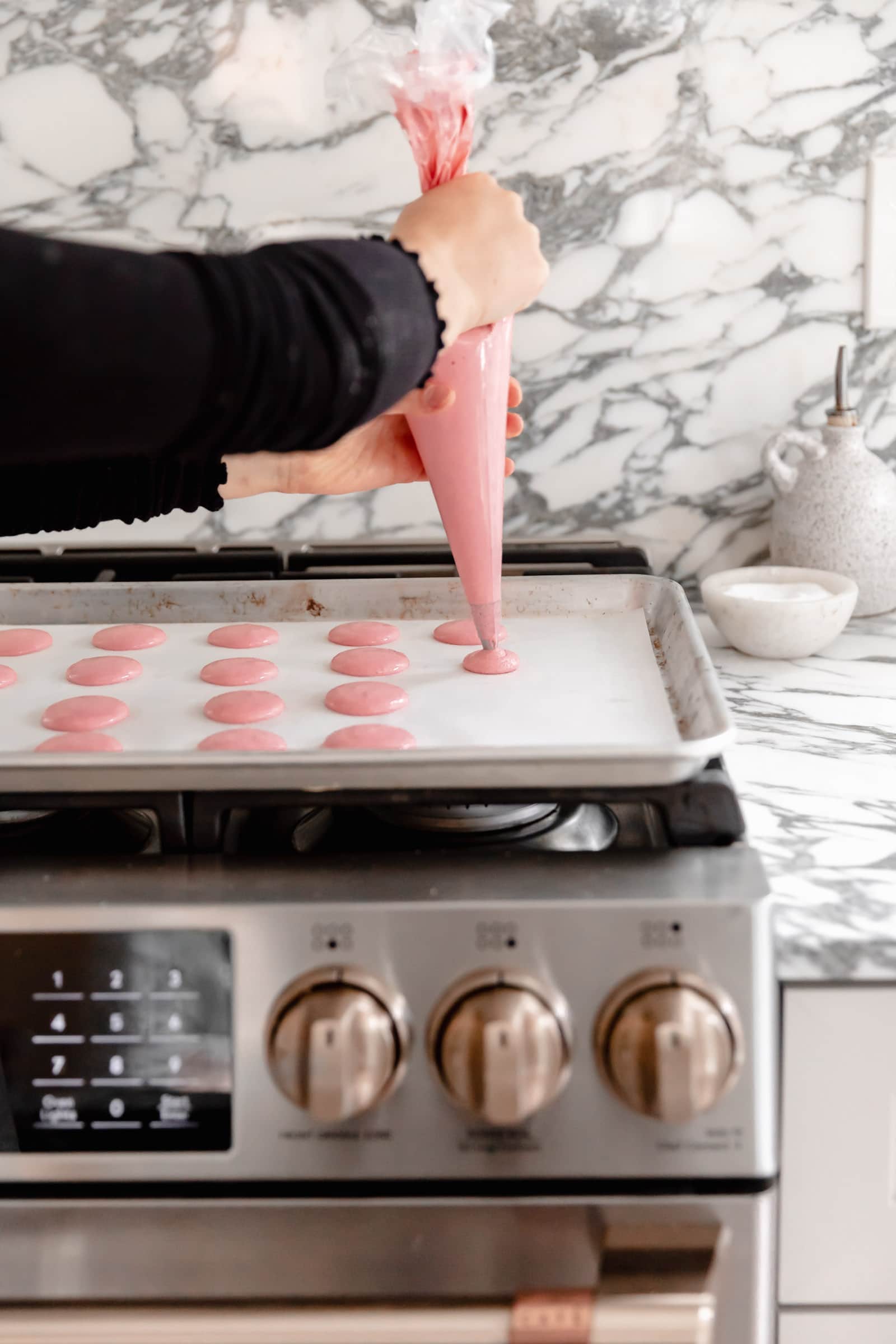 piping bag macarons on cookie sheet