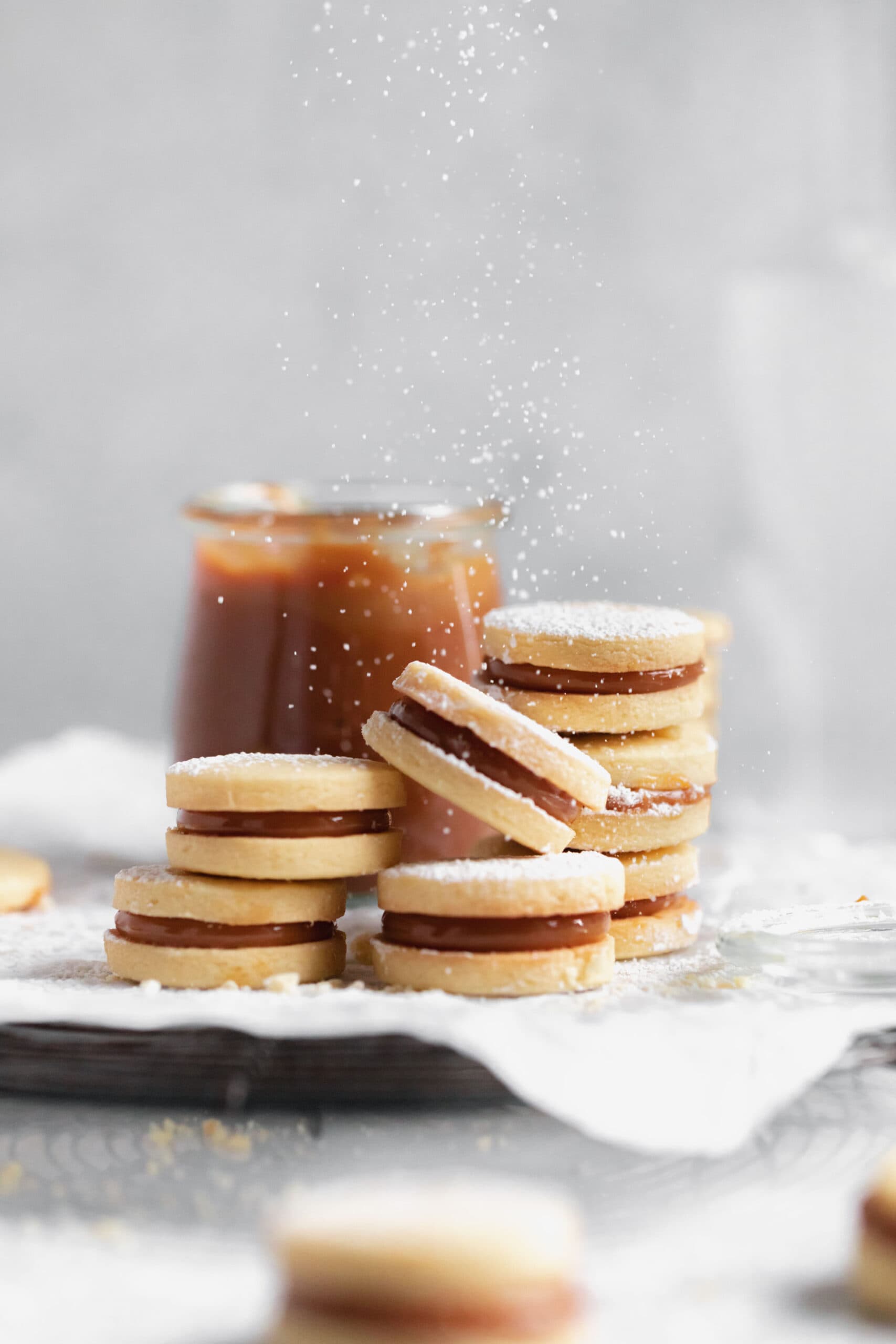 powdered sugar dusting onto dulce de leche sandwich cookies