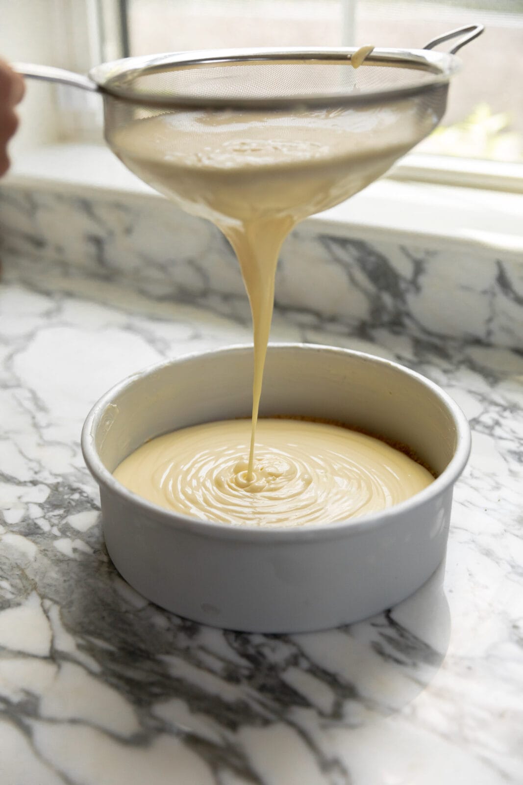 cheesecake batter straining into a pan