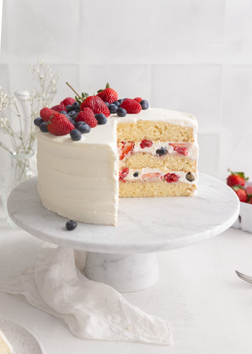 A cake with berries and cream on a white table